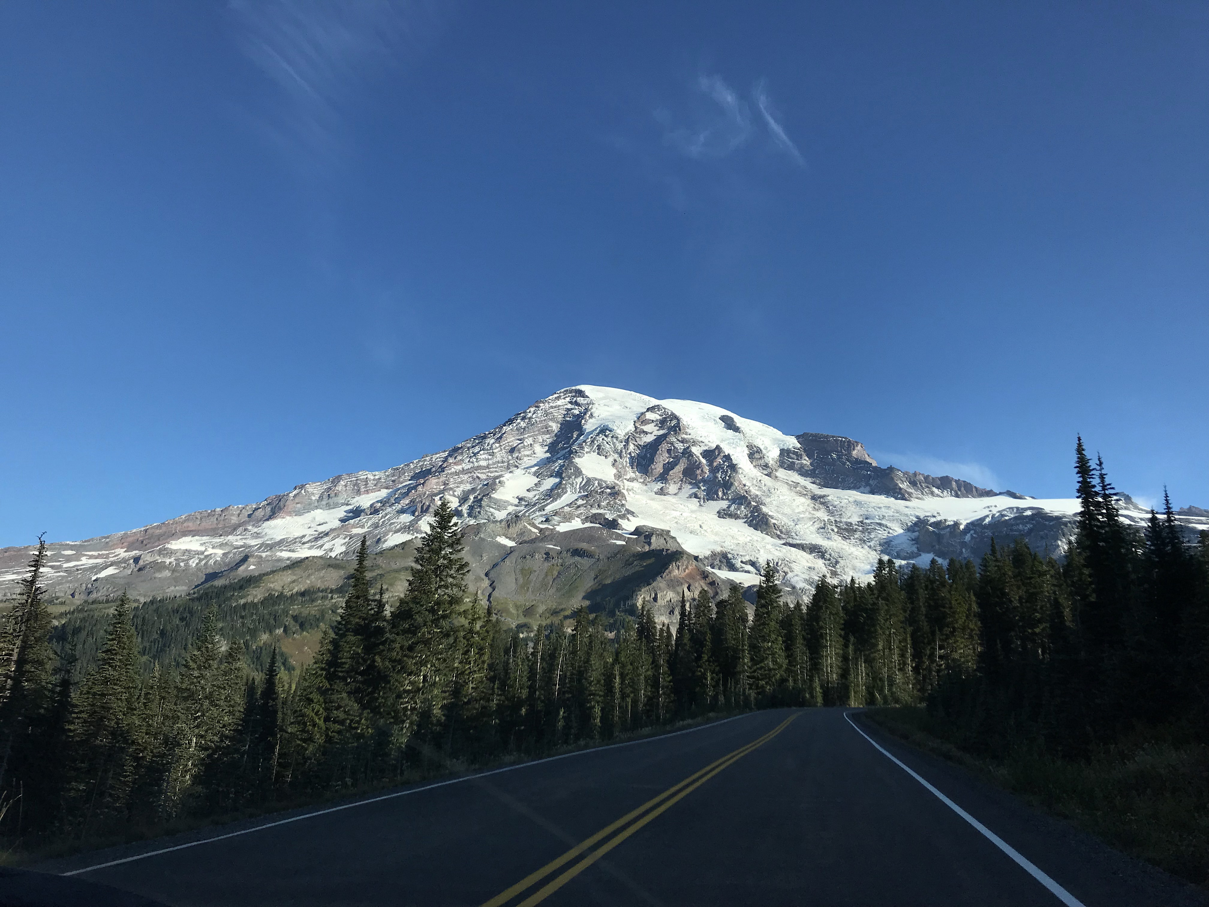 A road leads towards a glaciated mountain peak.