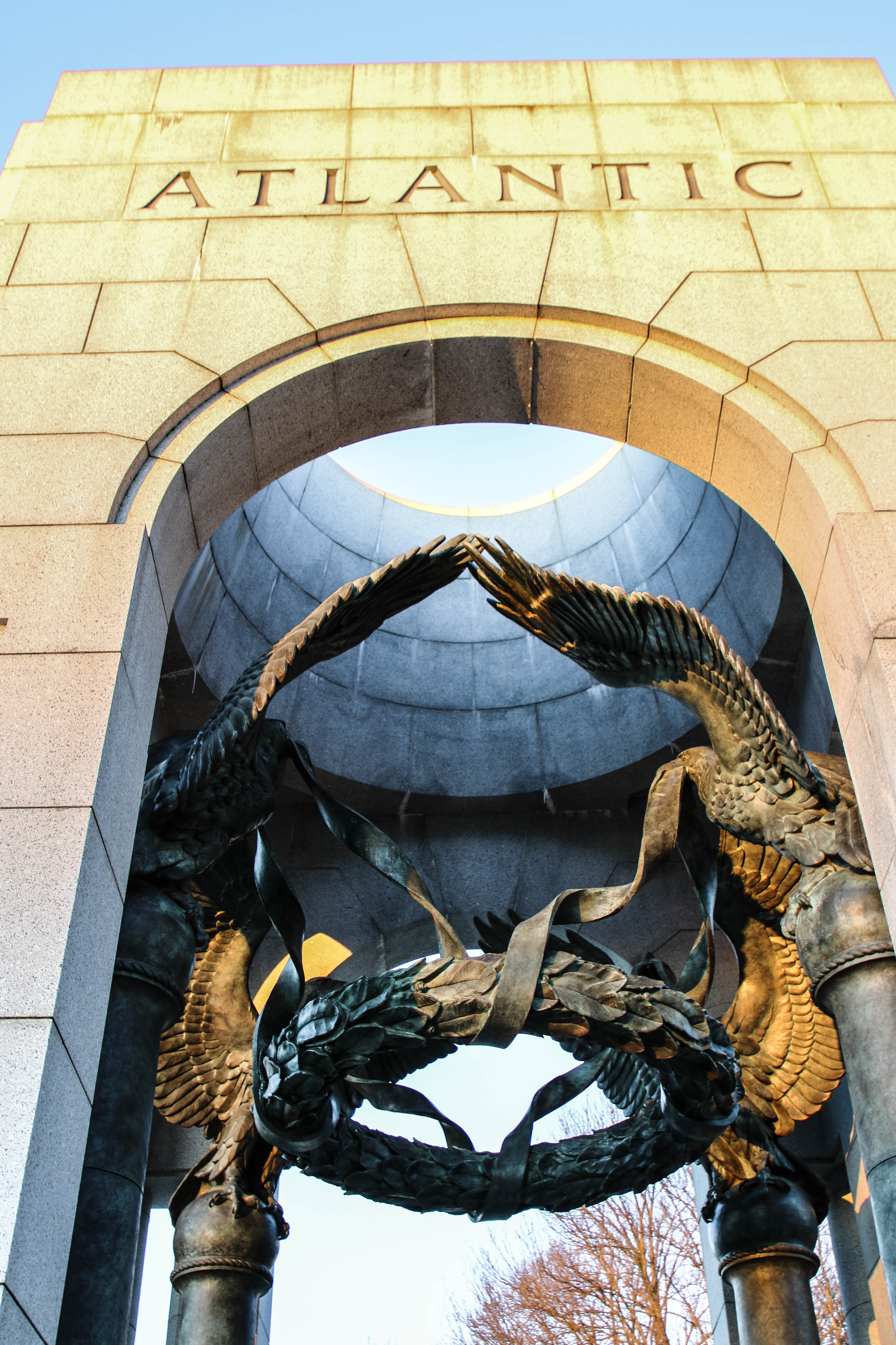 Bronze sculpture of eagles laying a laurel wreath under a stone arch.