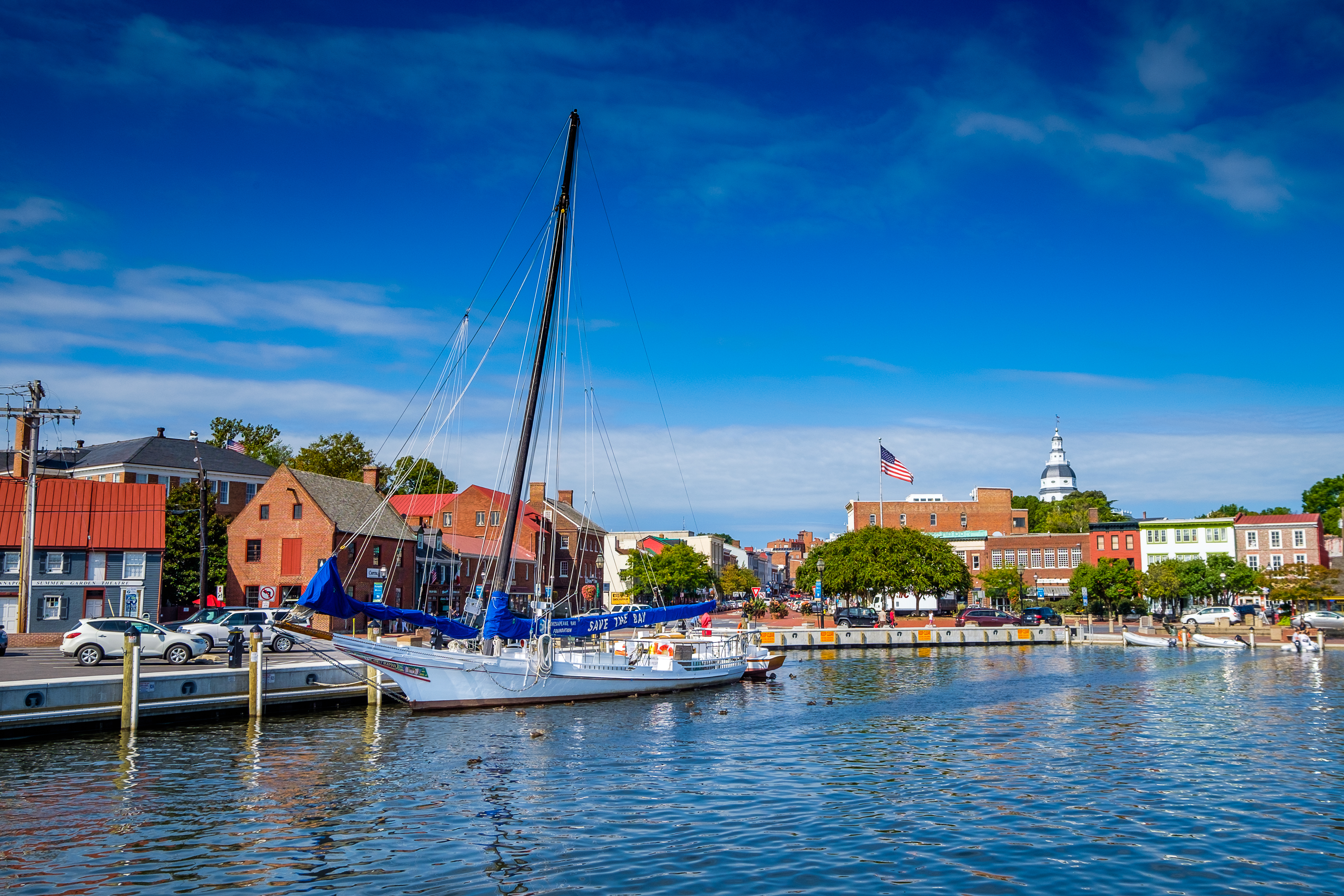 A boat in a harbor with brick buildings behind it.