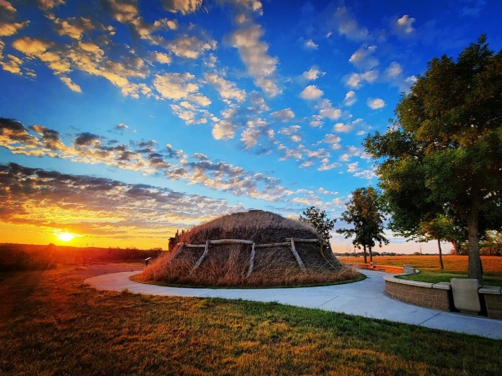 A brown, dome shaped lodge with a daisy chain of logs supporting sod covering on the sides and roof.