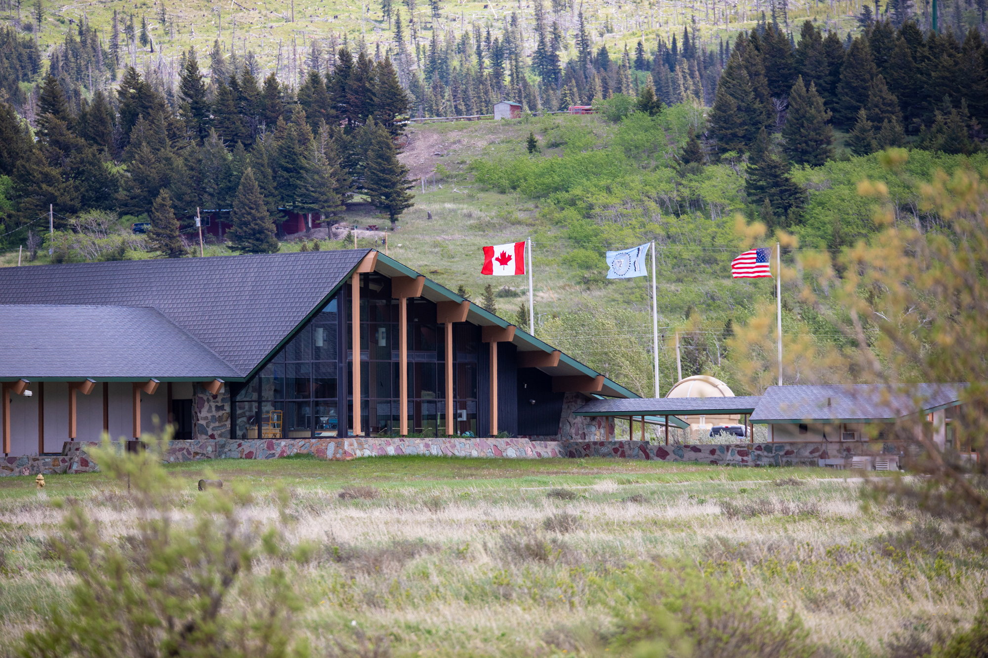 The large rear-windows of the St. Mary Visitor Center with flags flying behind.