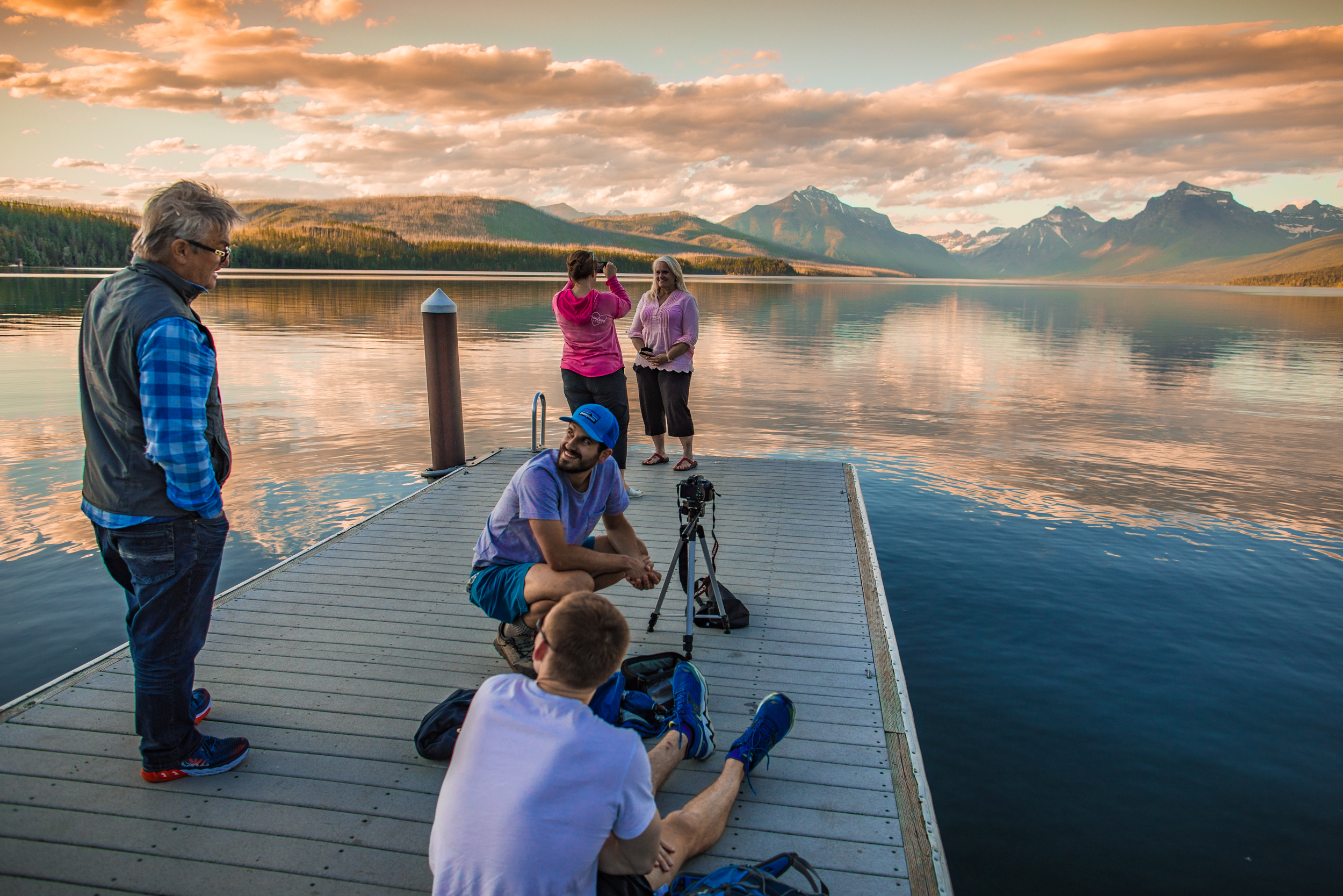 A group of park visitors cluster together on a boat dock in a large lake.