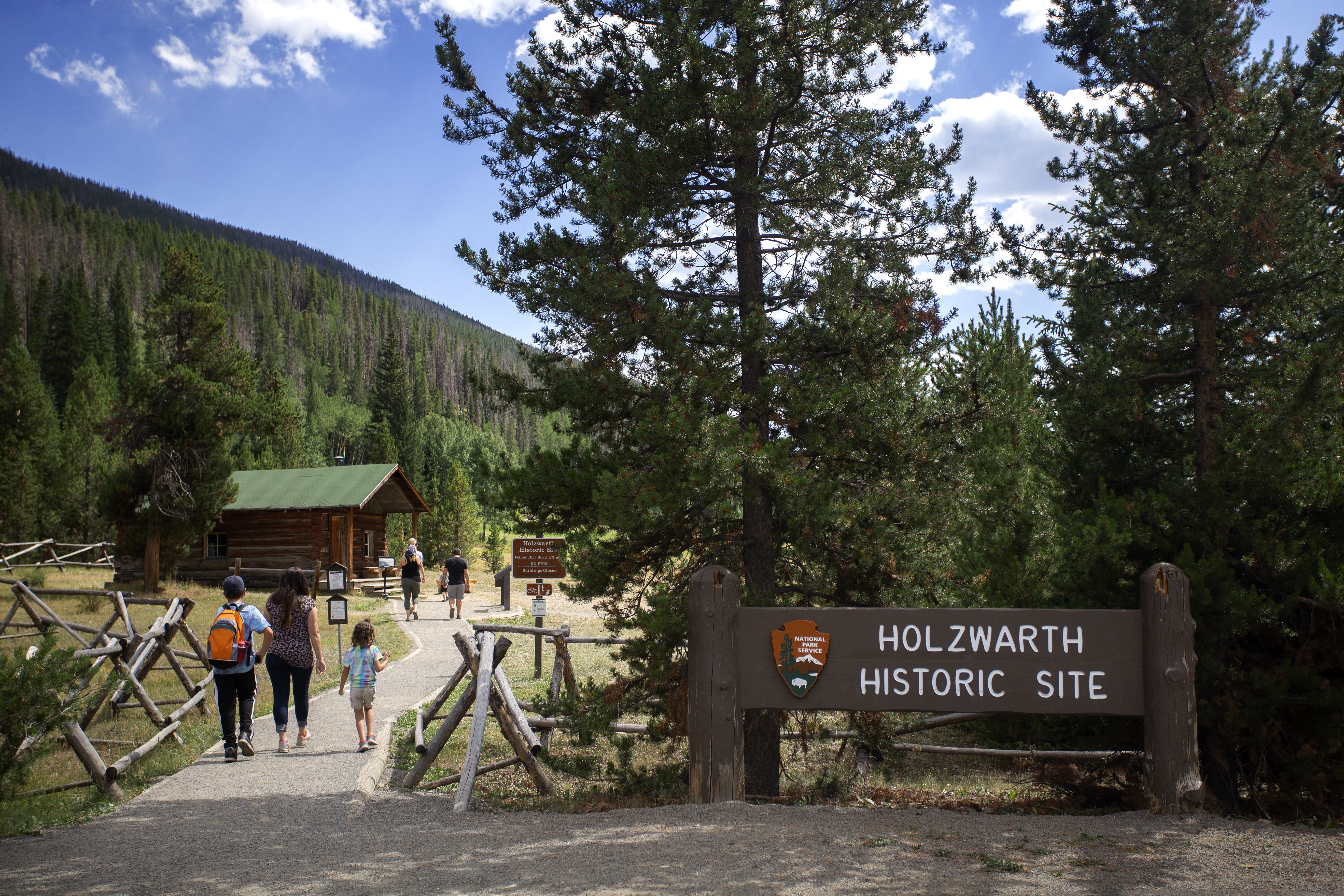 Visitors are walking on the dirt path, entering the Holzwarth Historic Site