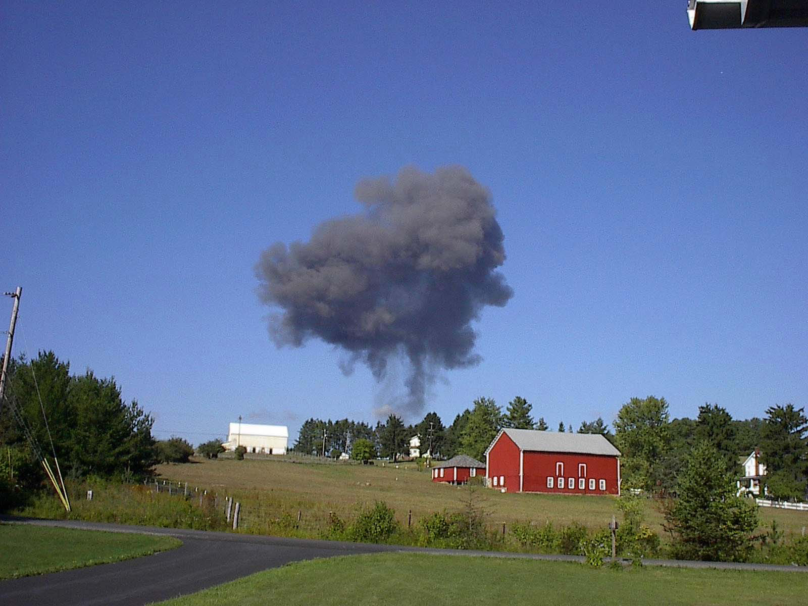 Image of smoke plume with red barn in the background.