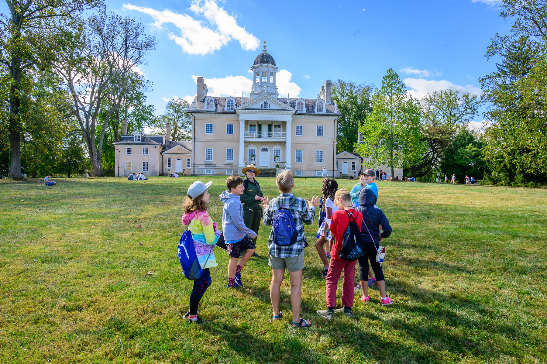 A view of the Hampton Mansion with visitors in front of it with ranger.