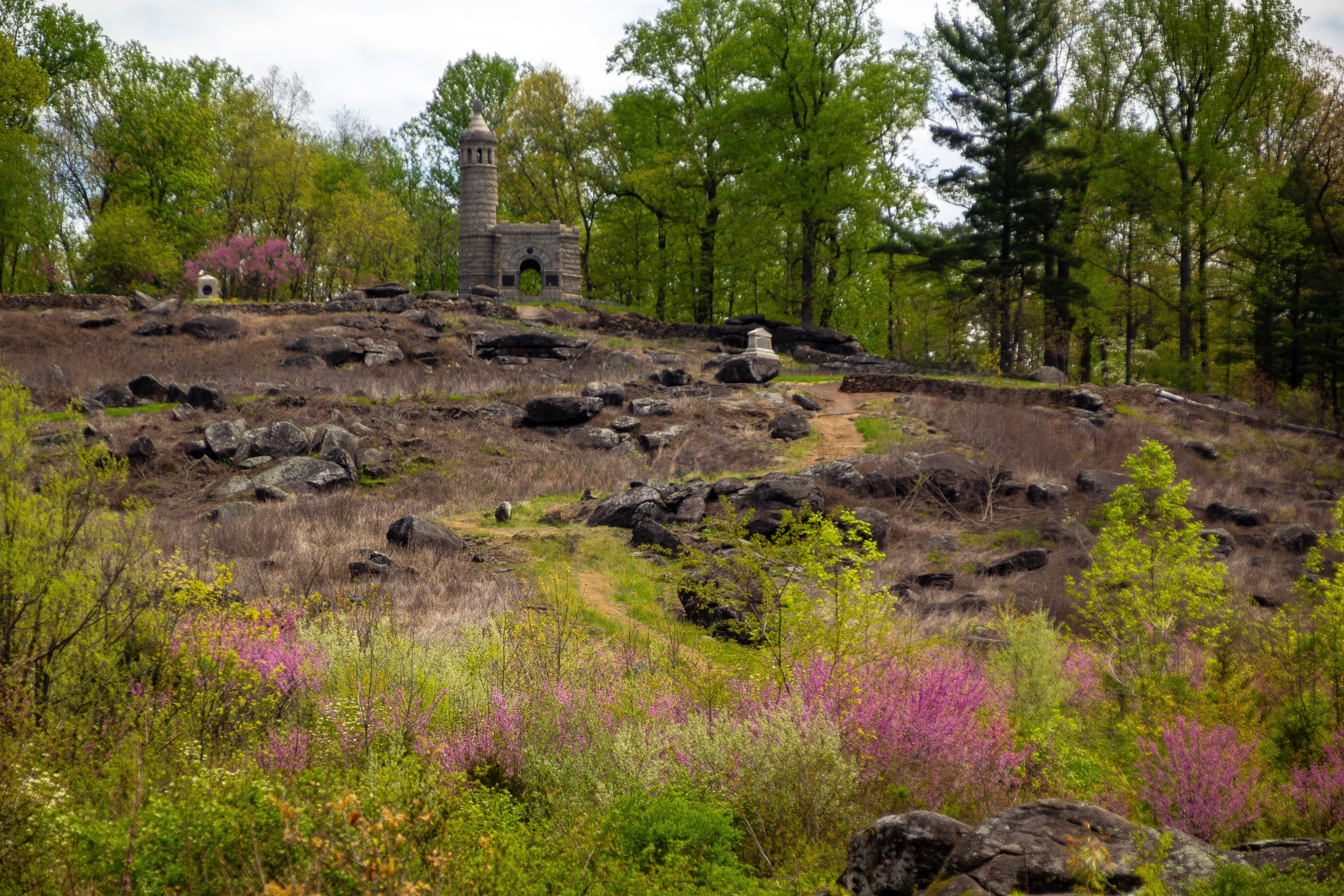 A dirt trail leads up to the summit of Little Round Top where there are 3 visible stone monuments.