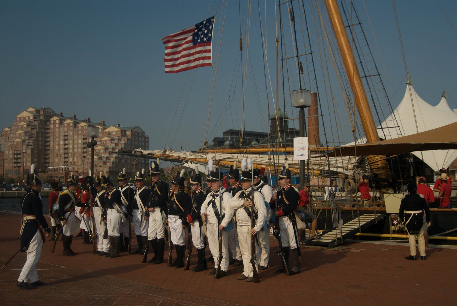 Pride of Baltimore docked in the Baltimore harbor with soldiers in kit in front of it
