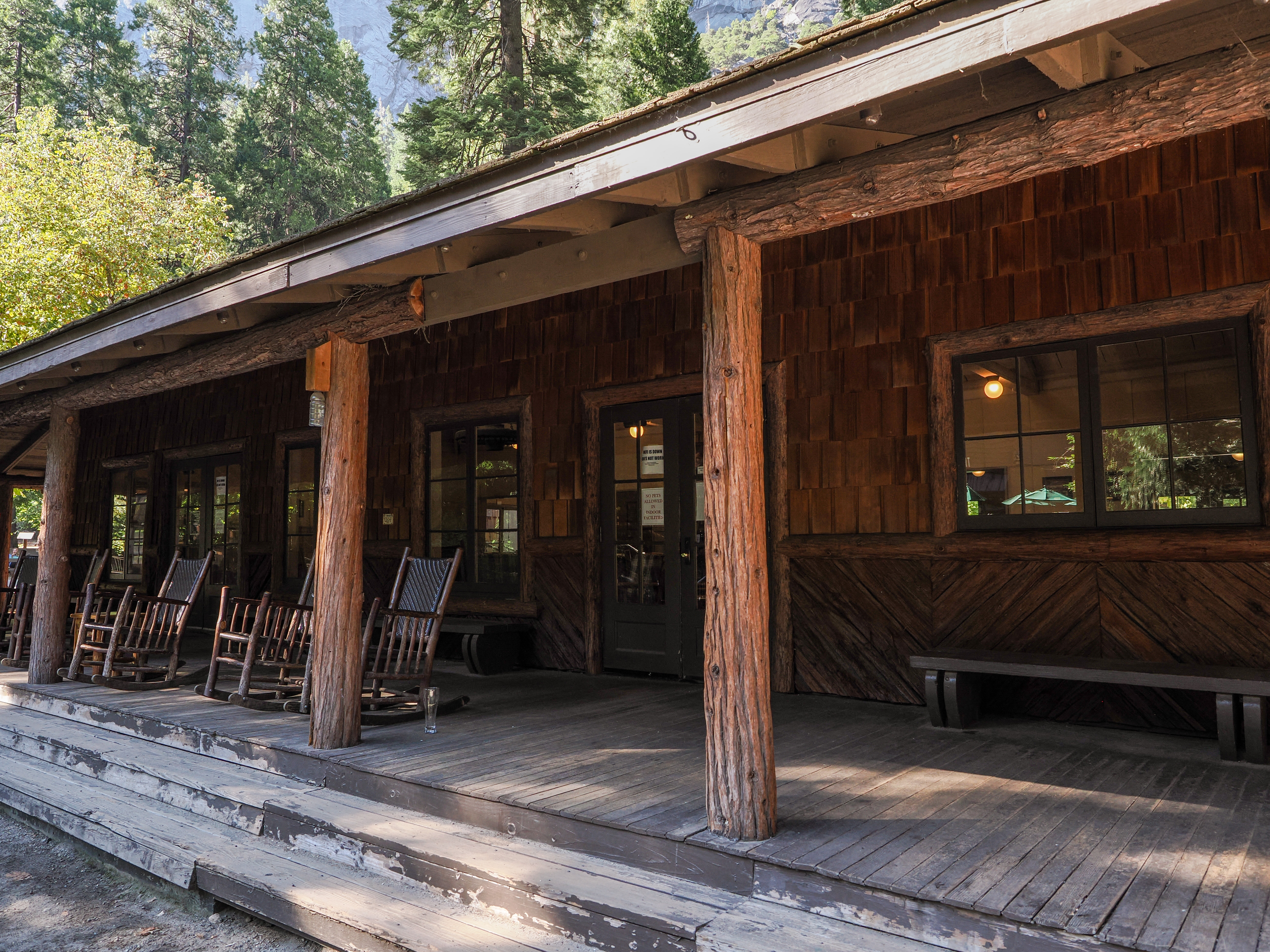 A single story building with a covered porch, unpeeled log accents, and shingles