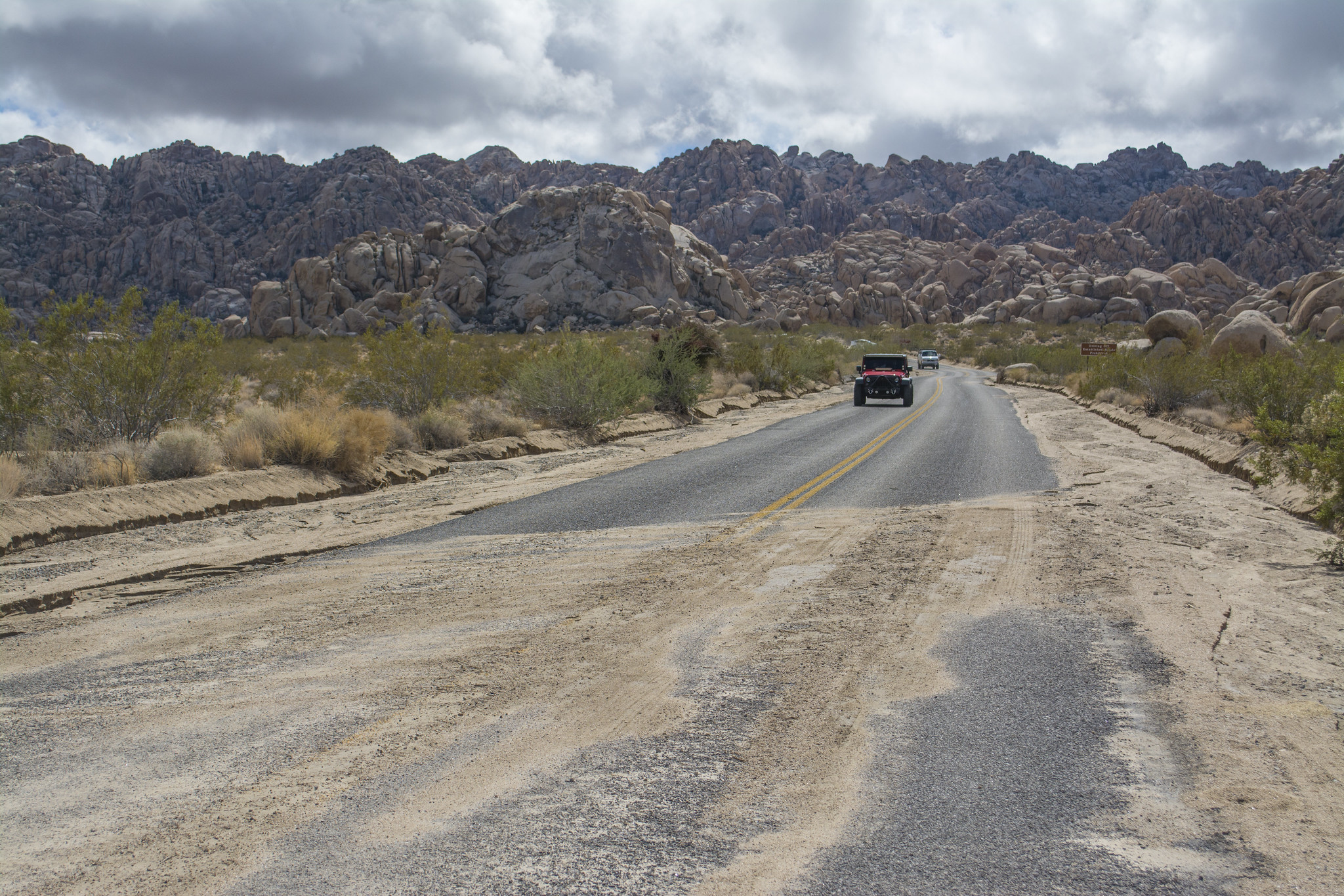 Sand covers a road that leads towards rocky crags