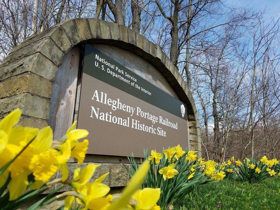 The park entrance sign with yellow flowers around it.