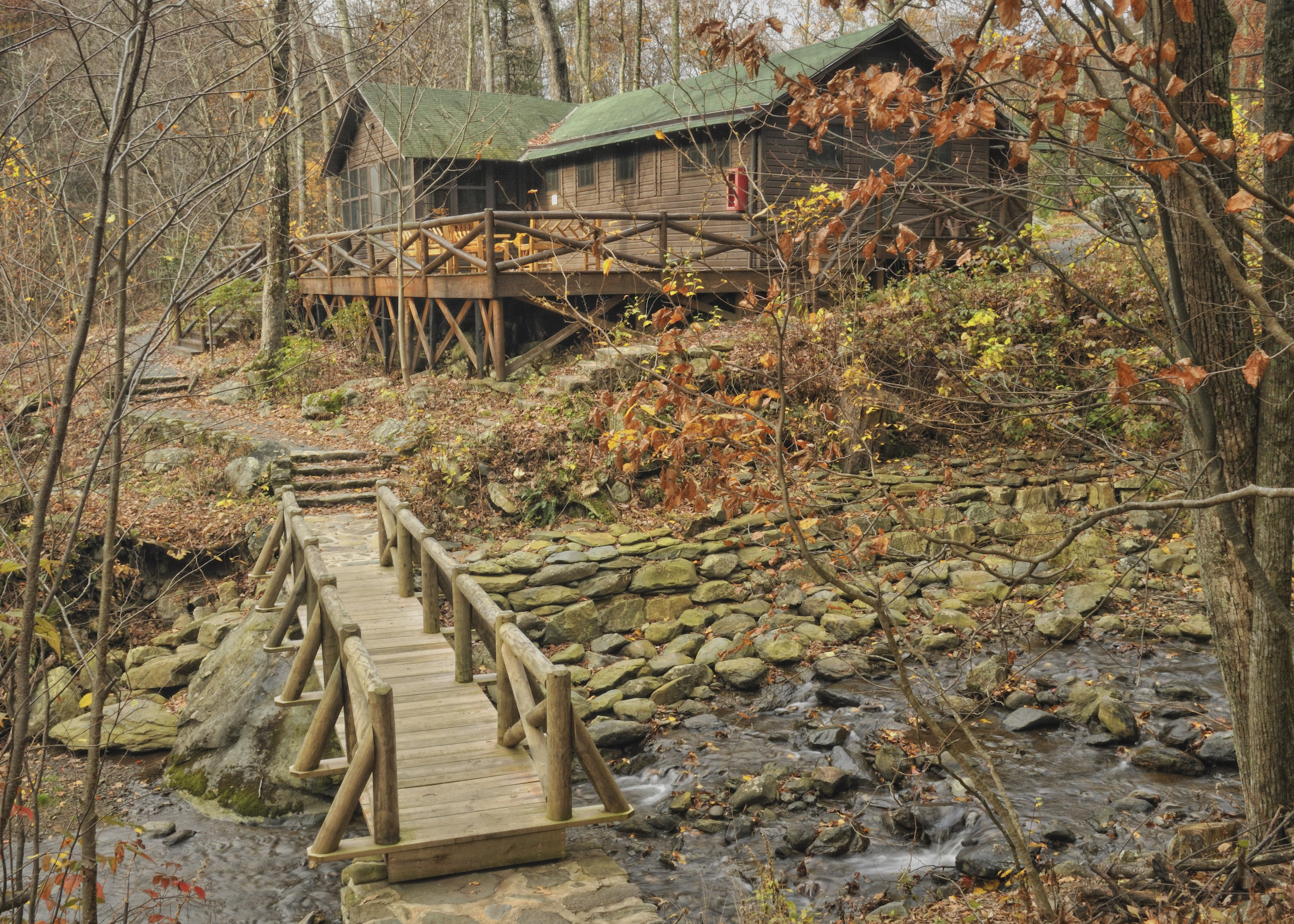 A fall scene with a creek and rustic bridge in the foreground and the