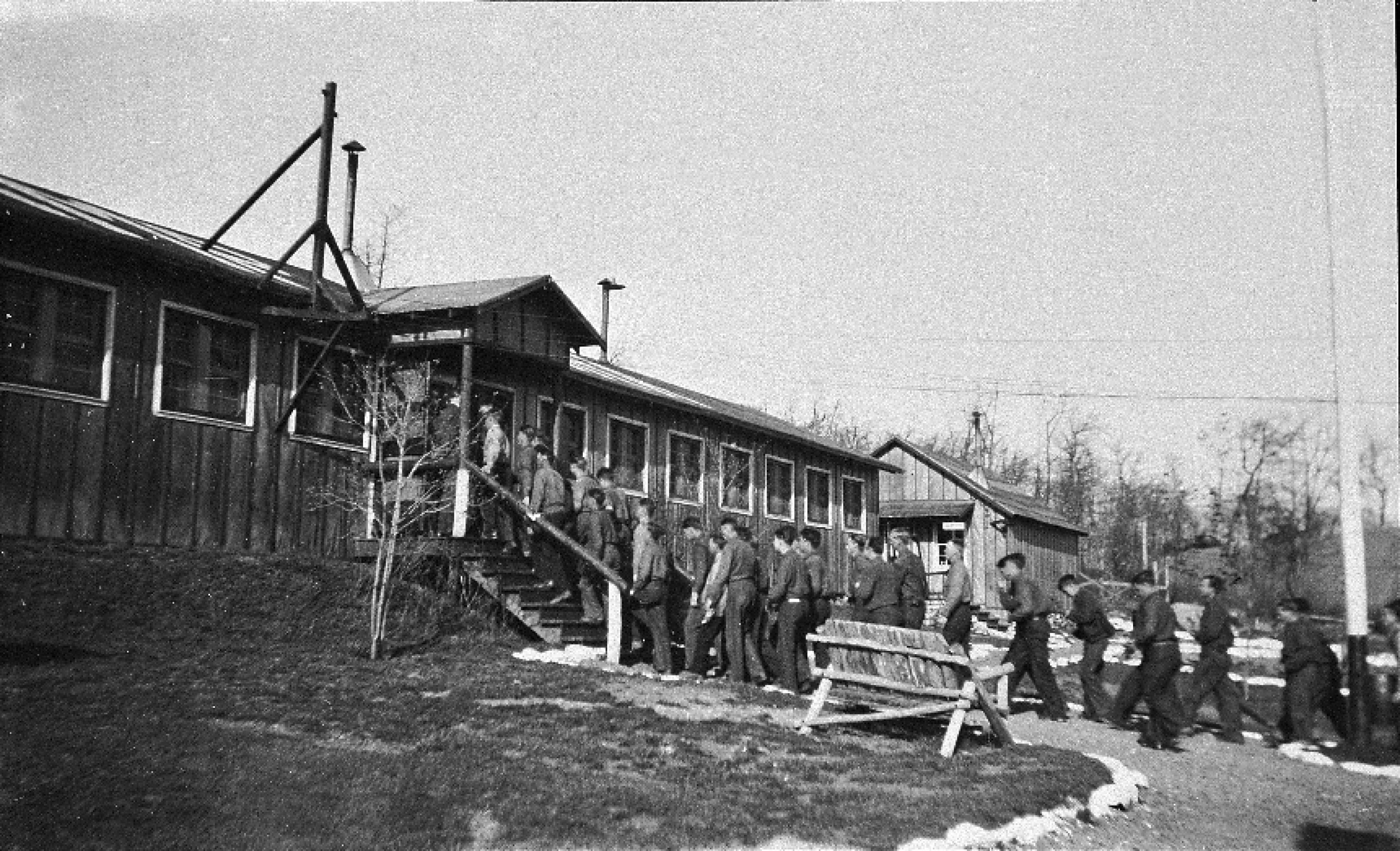 Young men lined up to enter a rustic building