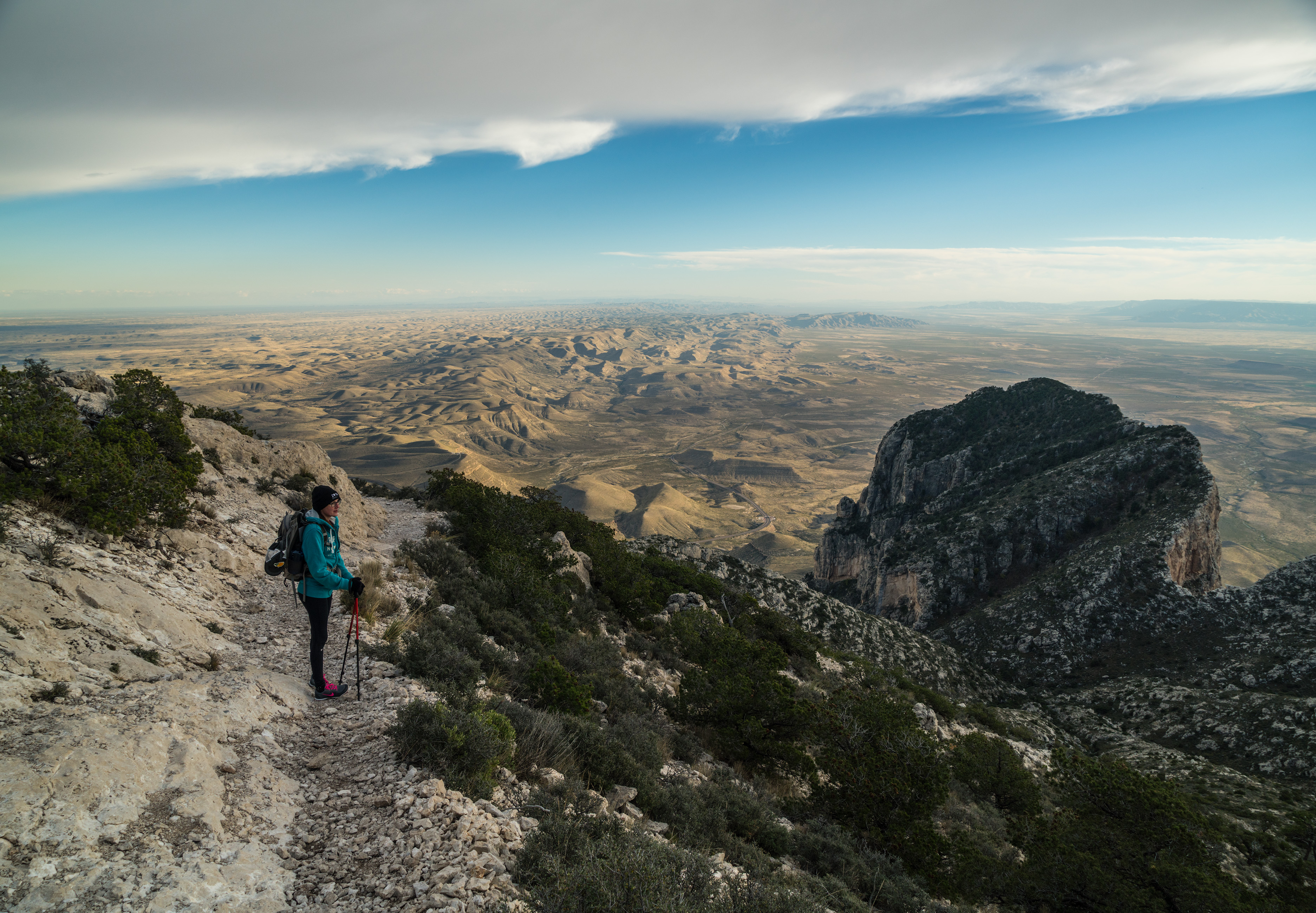 A hiker stands on the trail to Guadalupe Peak to the right the summit of El Capitan can be seen