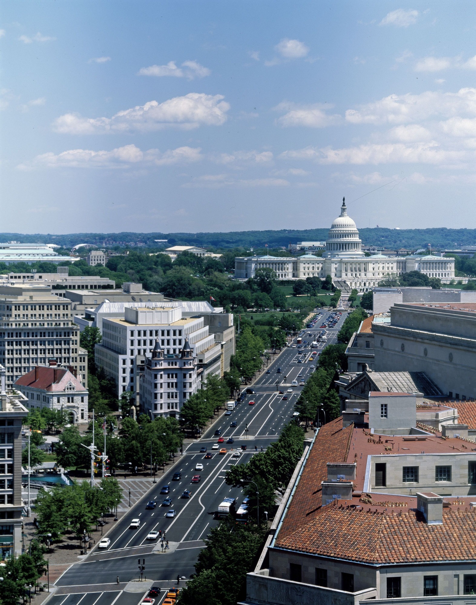 A six lane black-topped road stretching from the lower left to the upper right with US Capitol