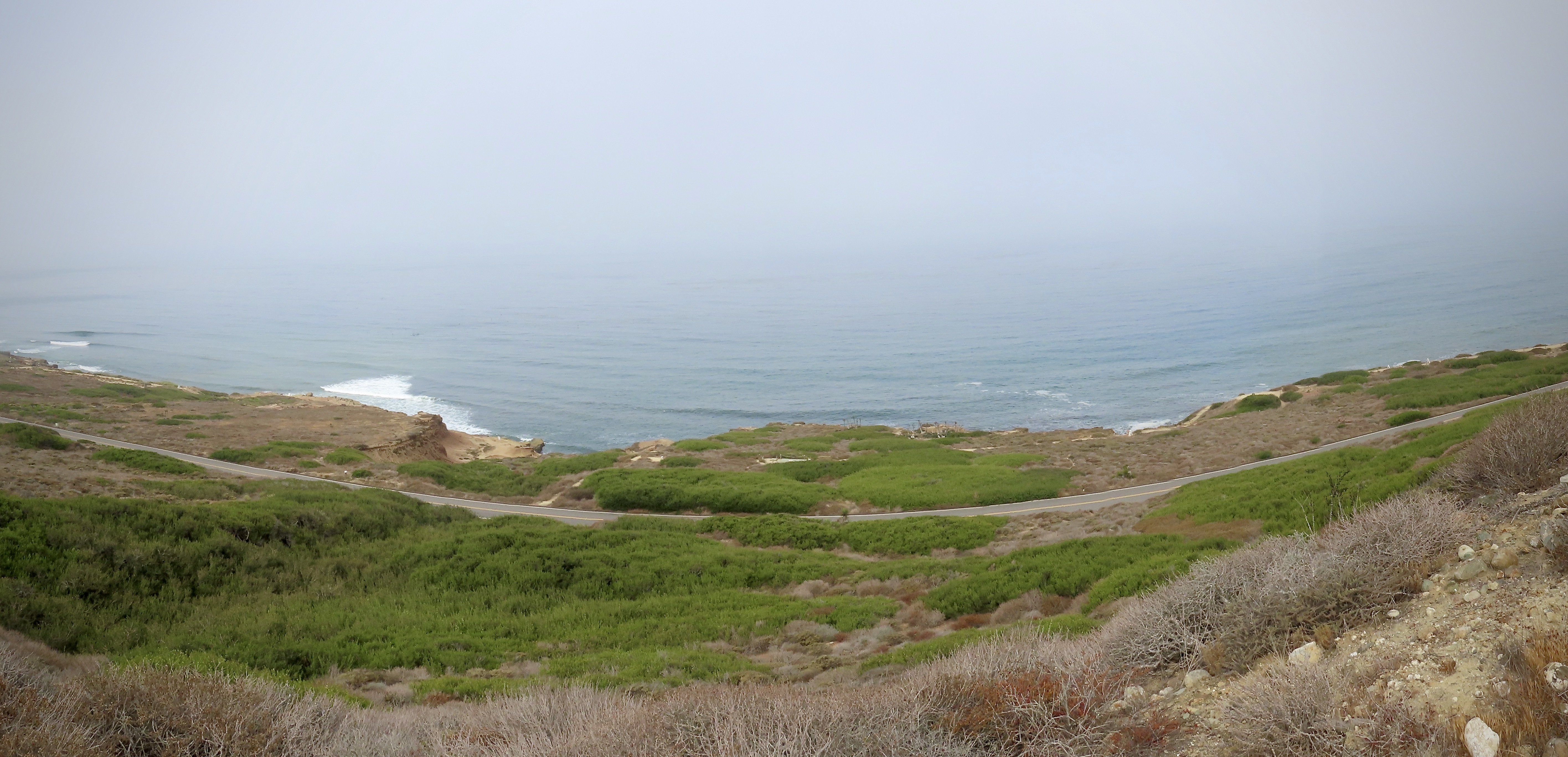 Dirt path along sandstone cliffs. Blue ocean is in background.