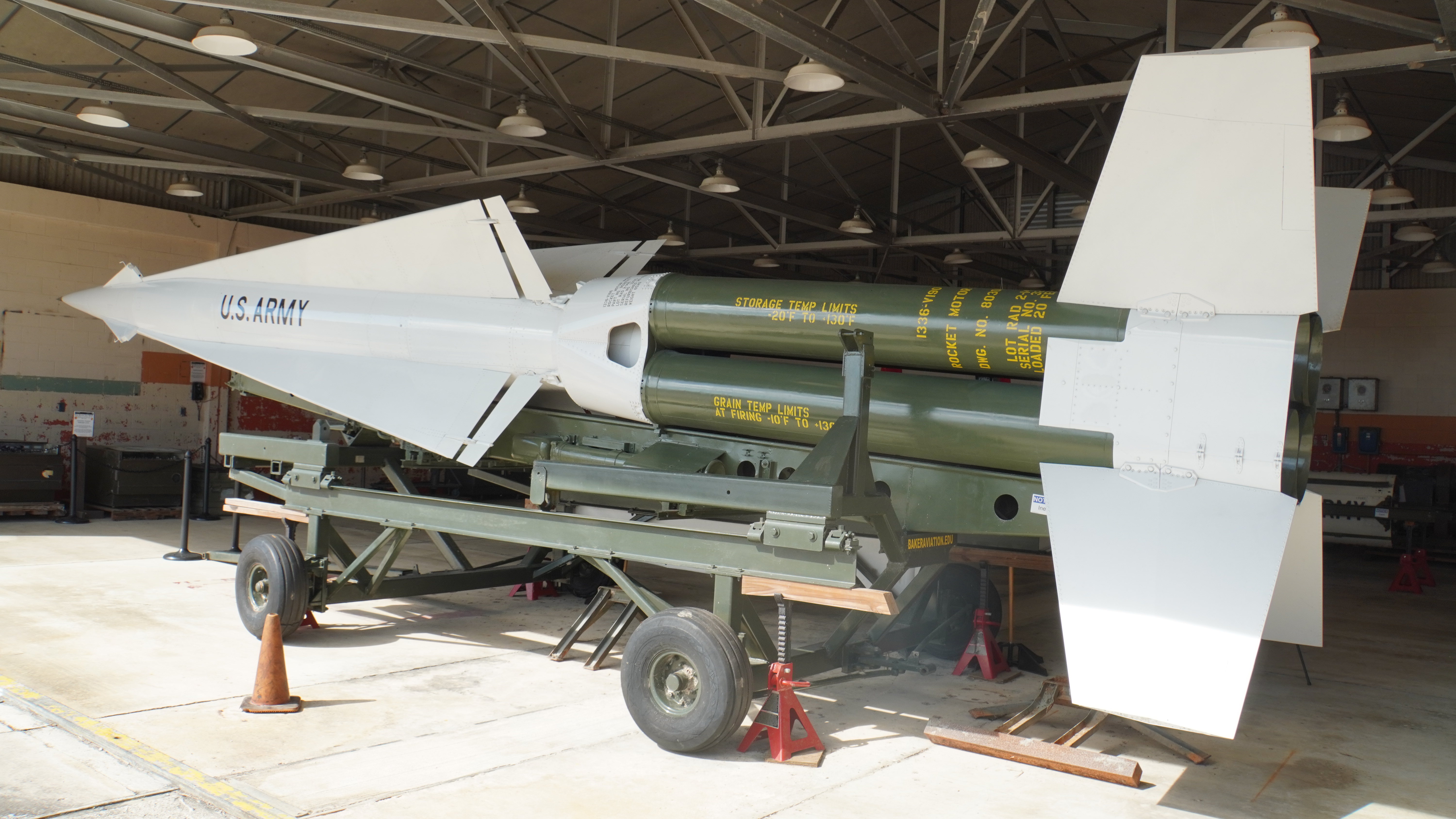A large green and white missile with the lettering 'US ARMY', sitting on a green wheeled carriage