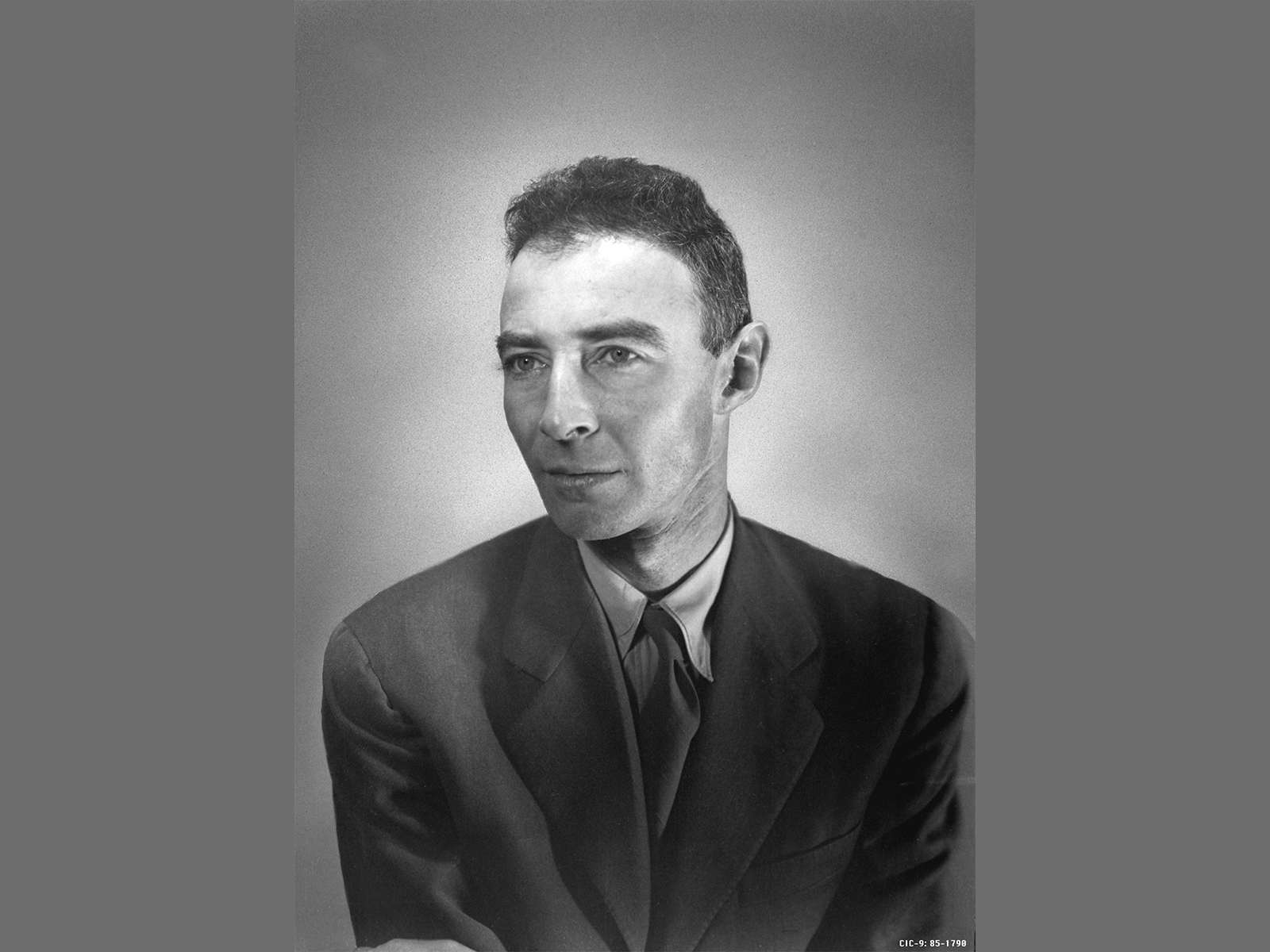 A black and white portrait photo of a man in a black suit jacket and tie.