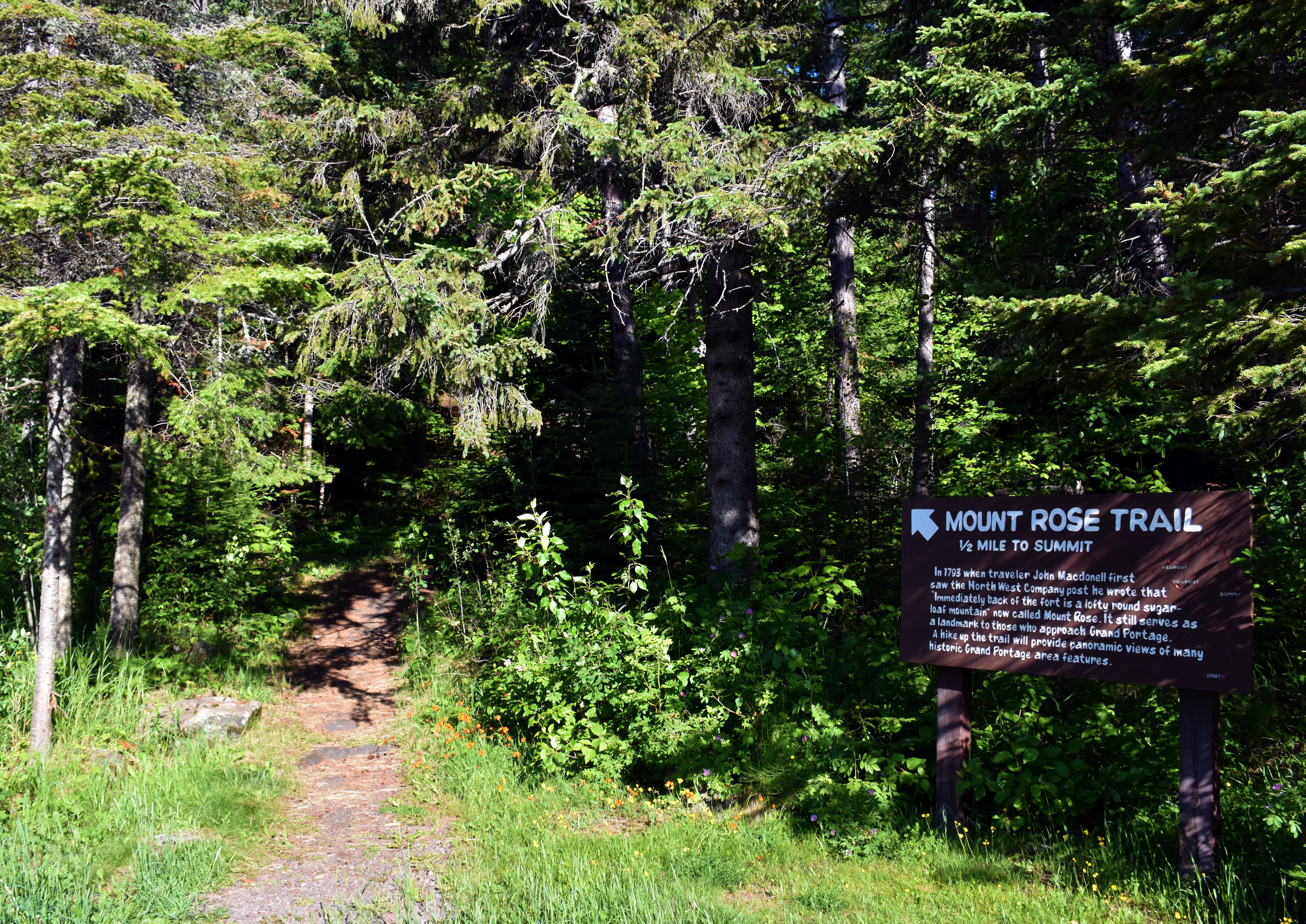 A wood sign with historical text about the landmark.