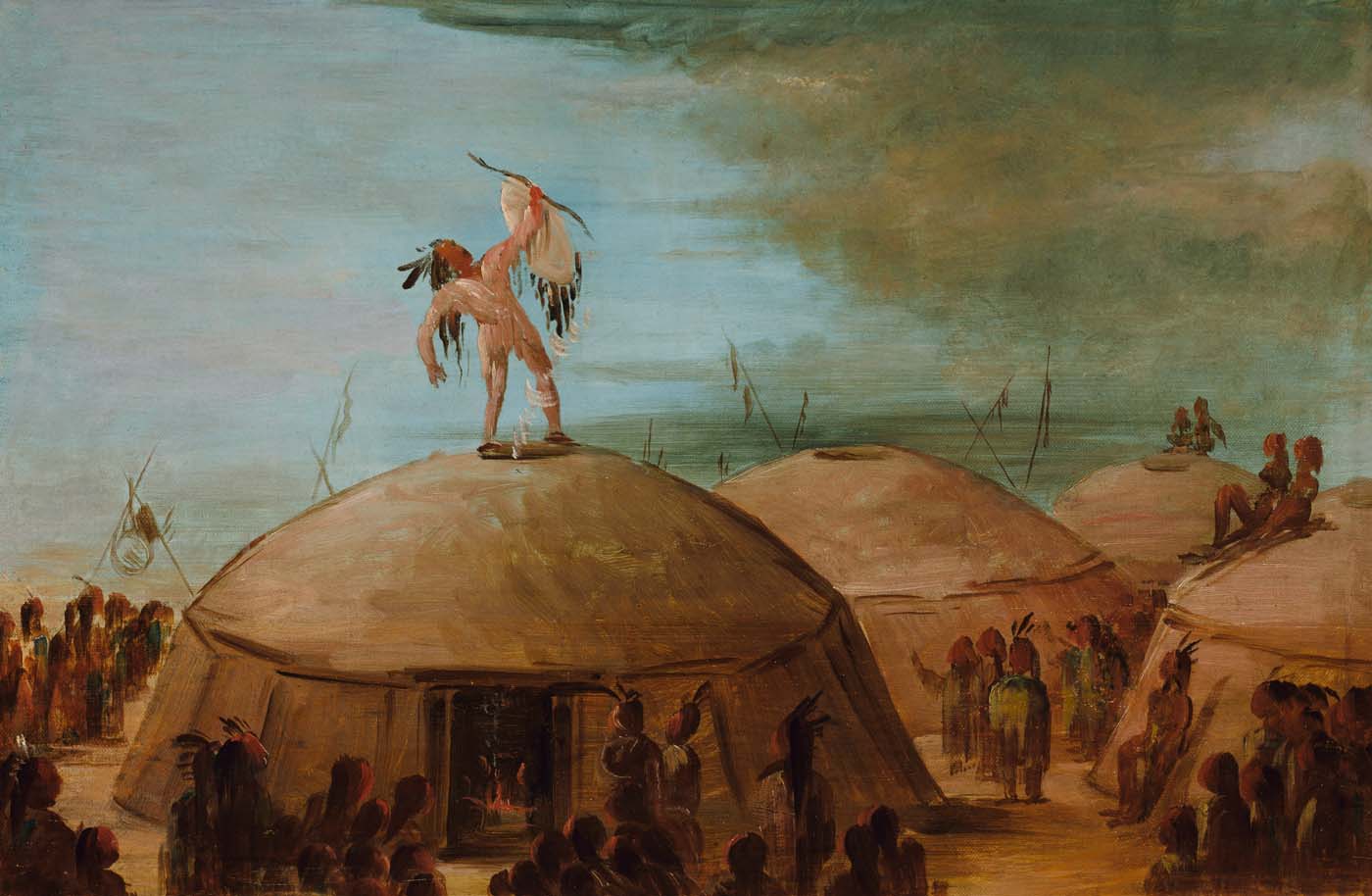 A man standing on an earthlodge in a village