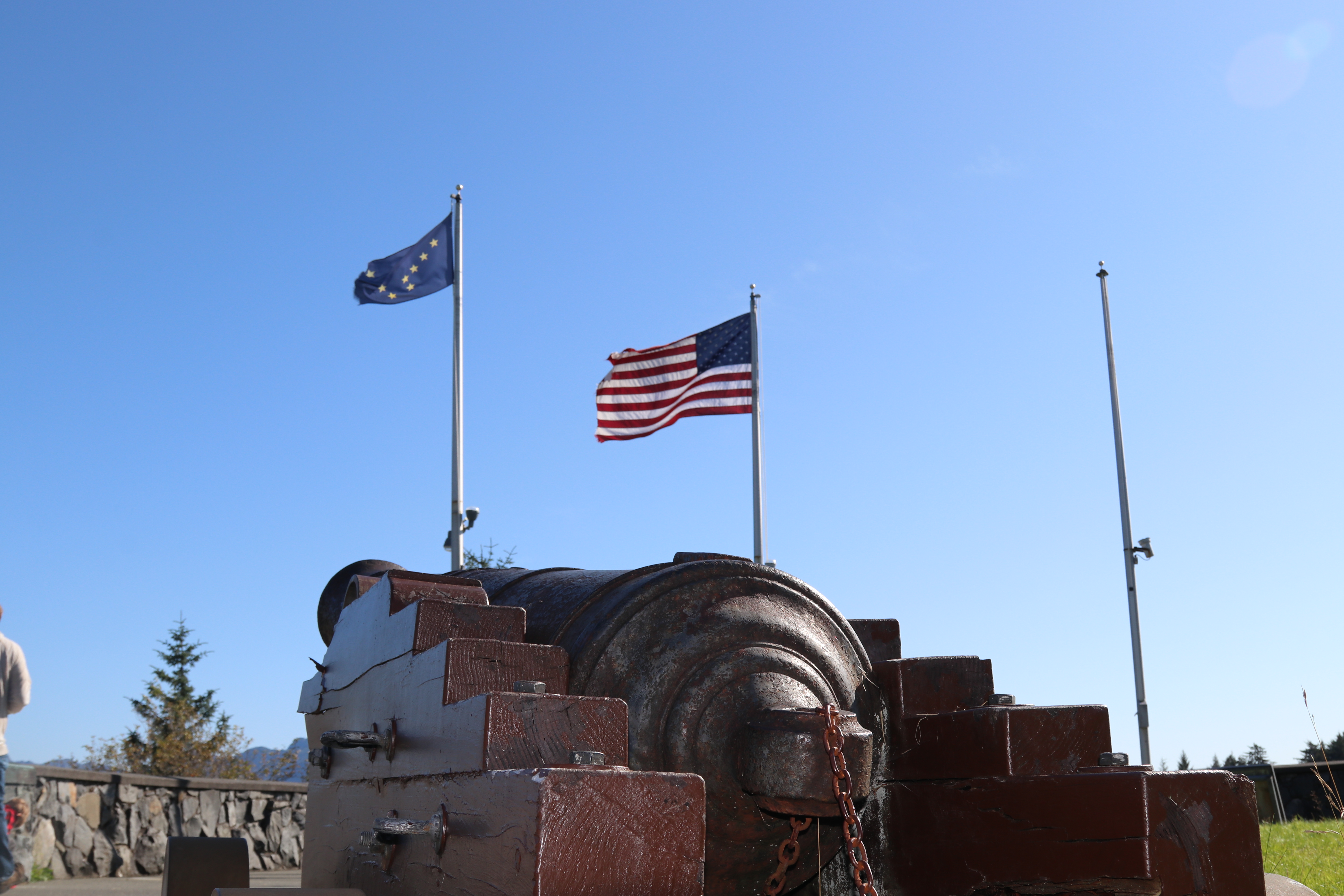 A historic canon in displayed below the American and Alaska State Flag.