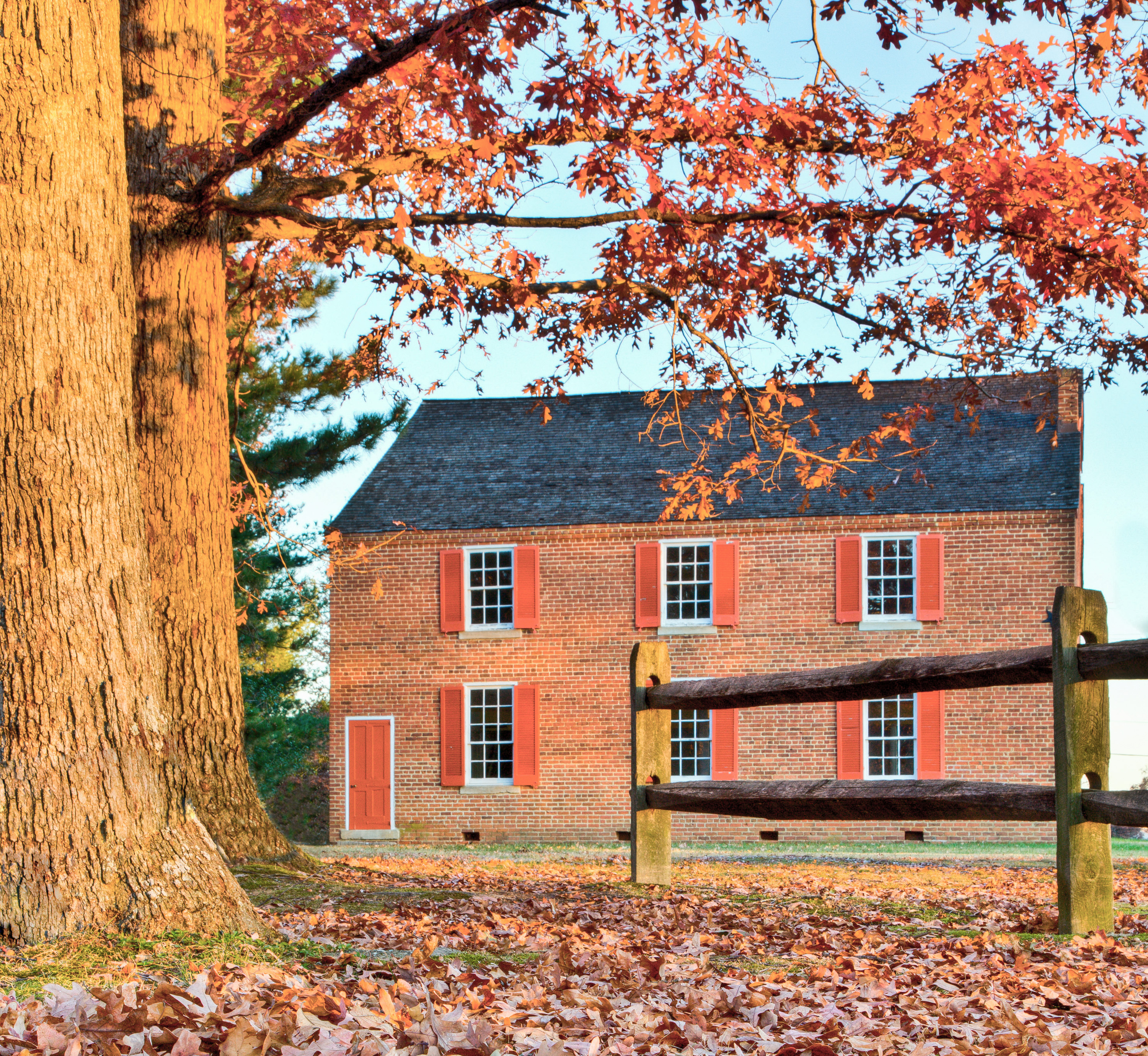 Fall photo through wooden fence of two story brick church.