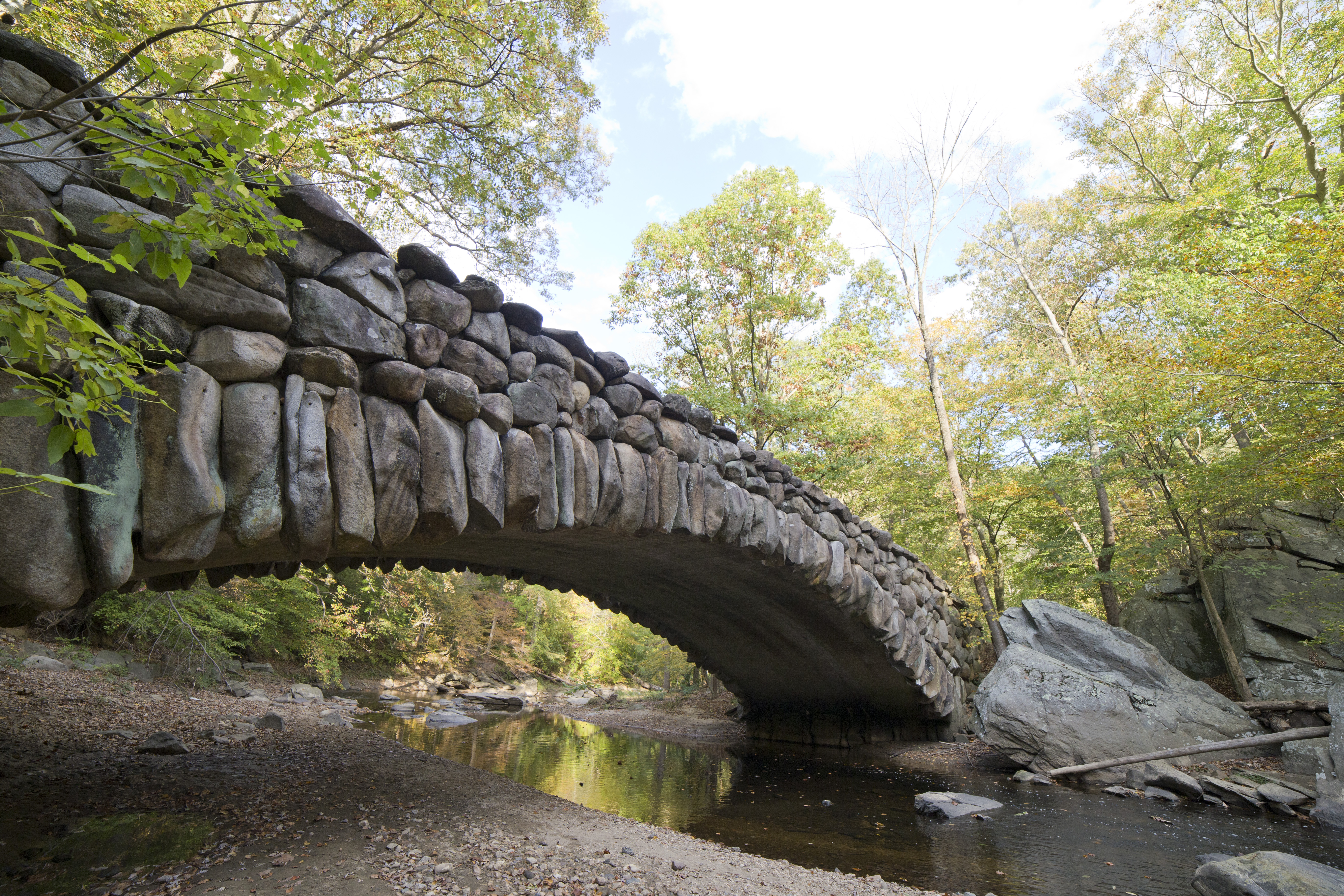 A bridge covered in rocks spans a creek