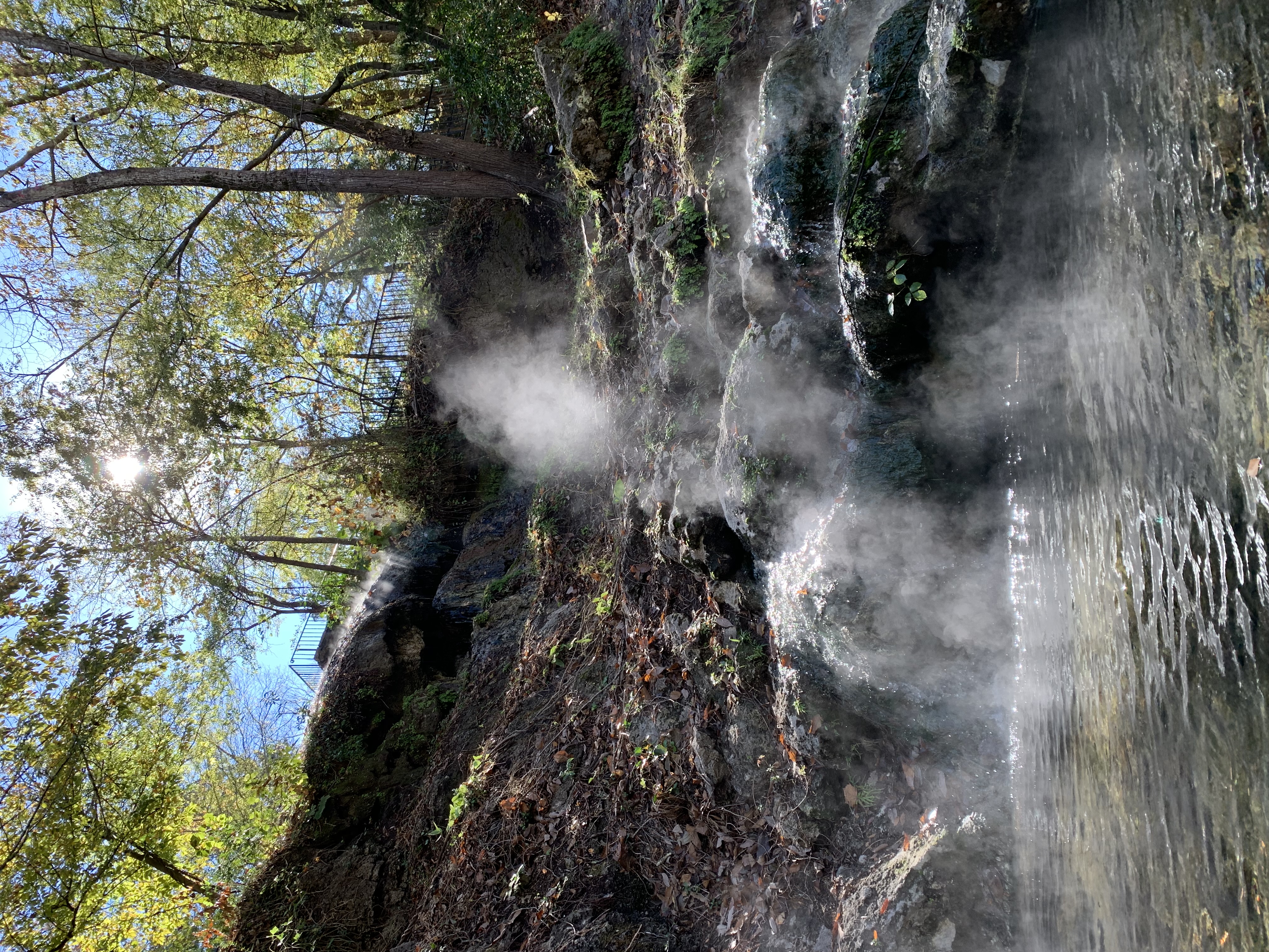 Sunlight shines on the steam of a small waterfall of hot water.
