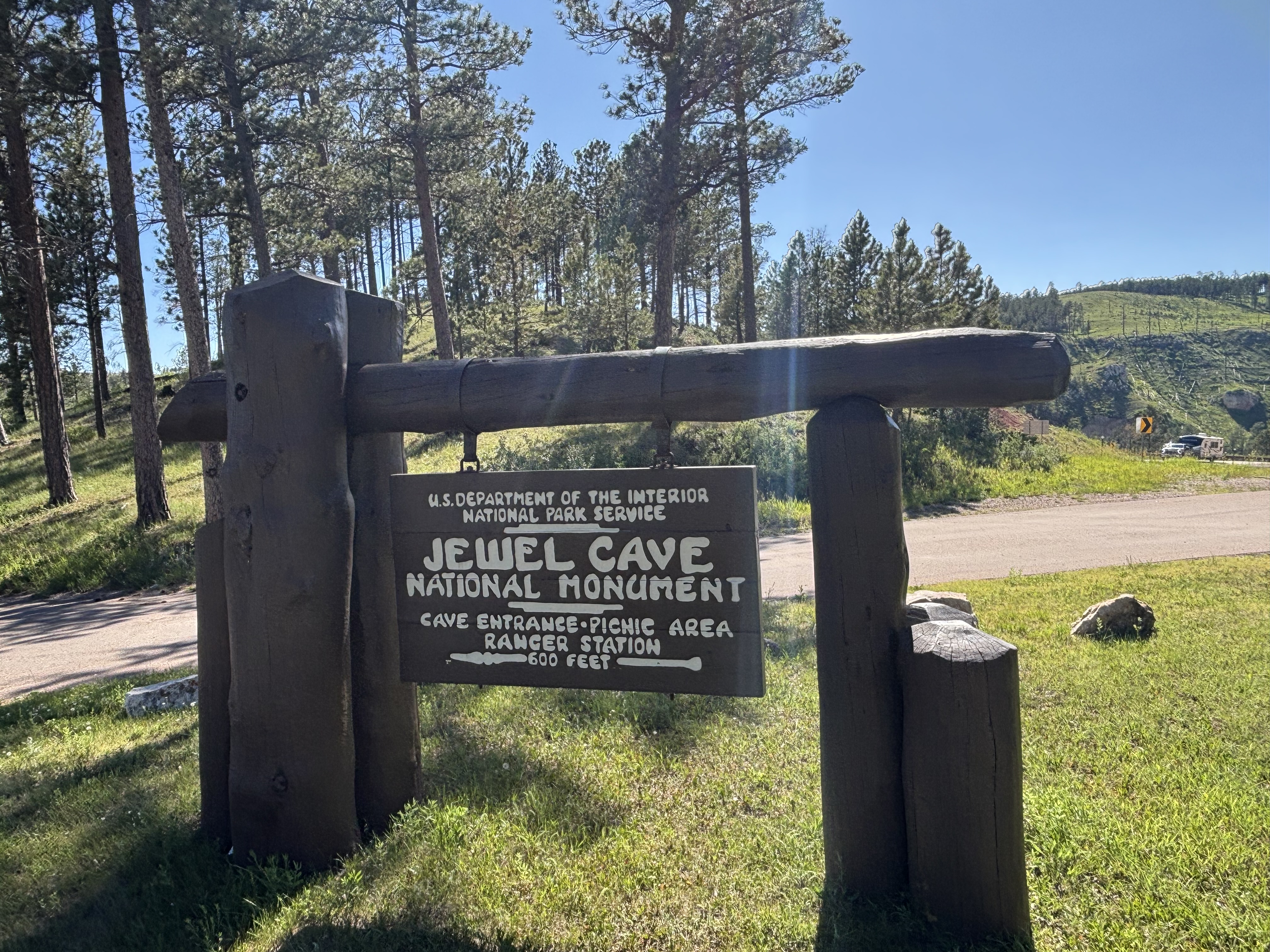 A wooden entrance sign on a grass median.