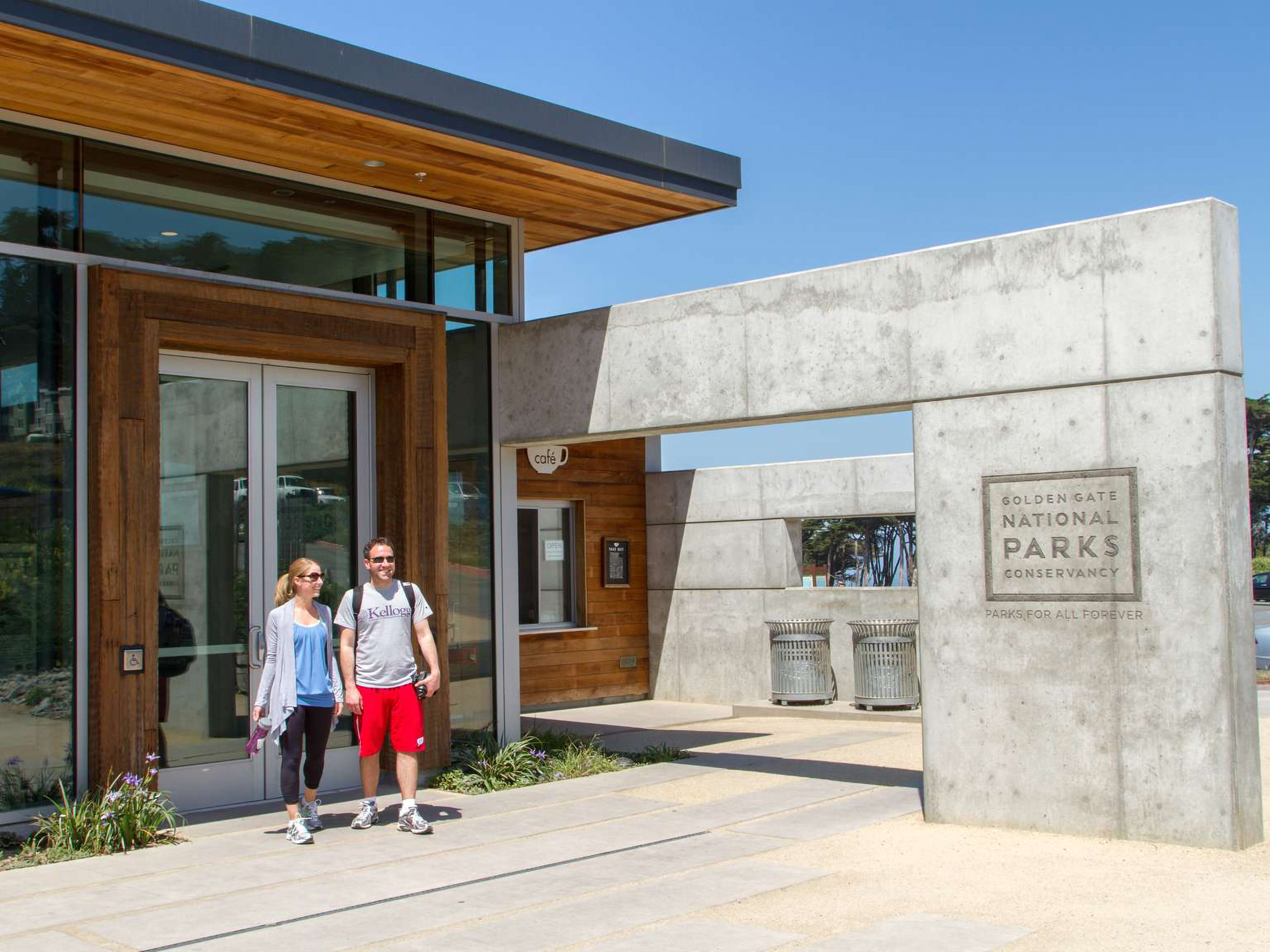 Colored photo of 2 visitors using the entrance to the Lands End Lookout Visitor Center