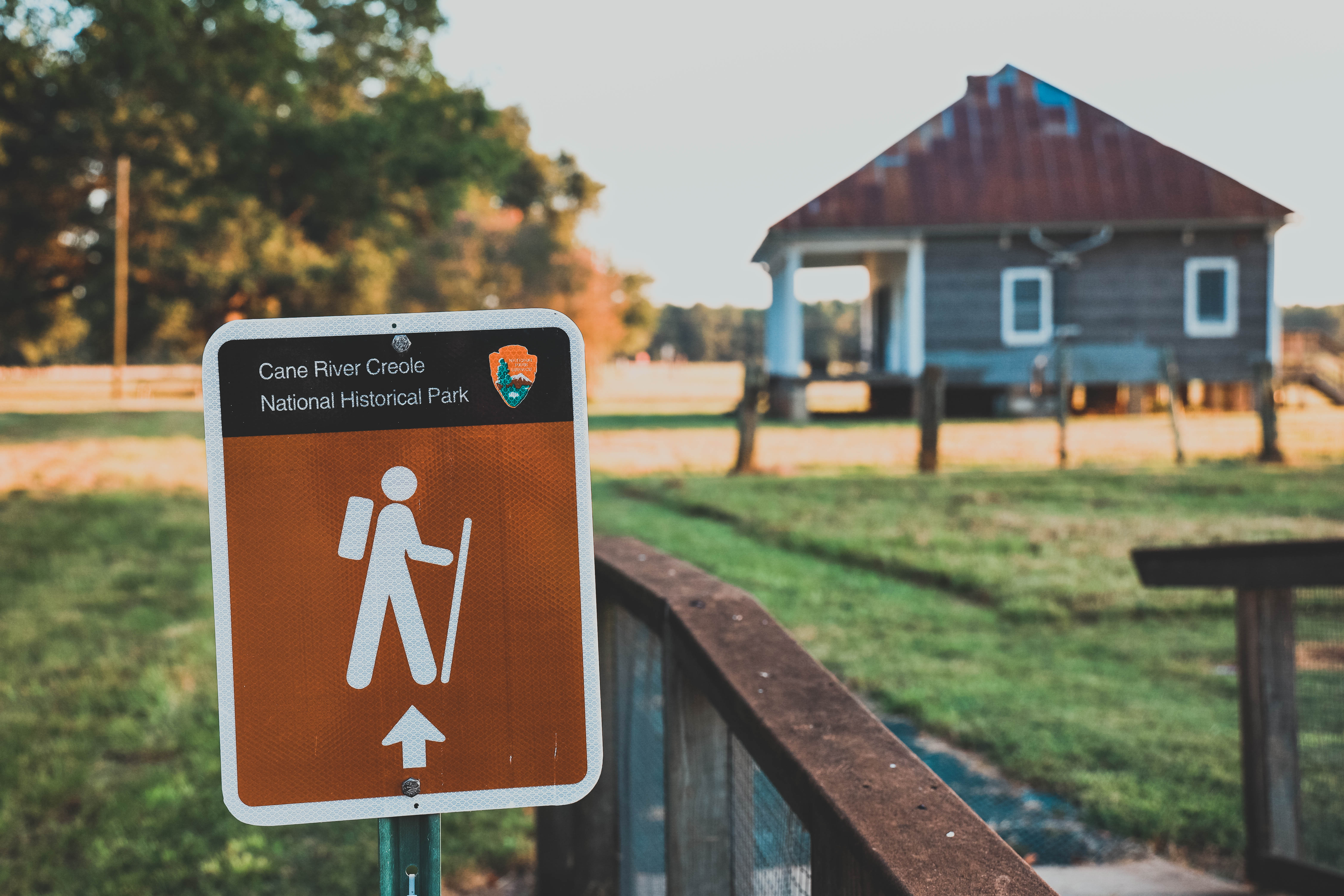 Brown trail sign with Oakland Overseer's House in background.