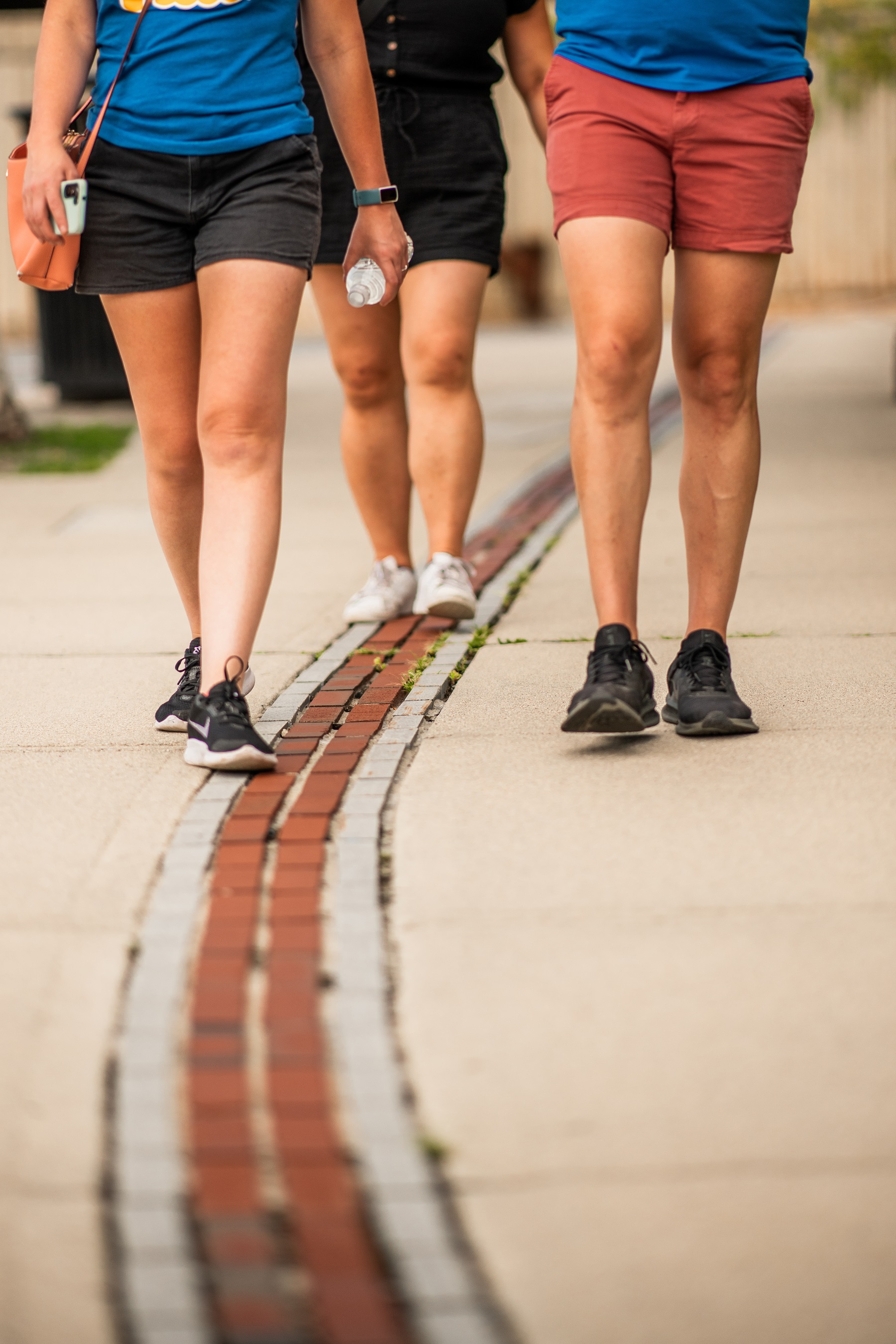 People walking along a red brick line paved in cement.