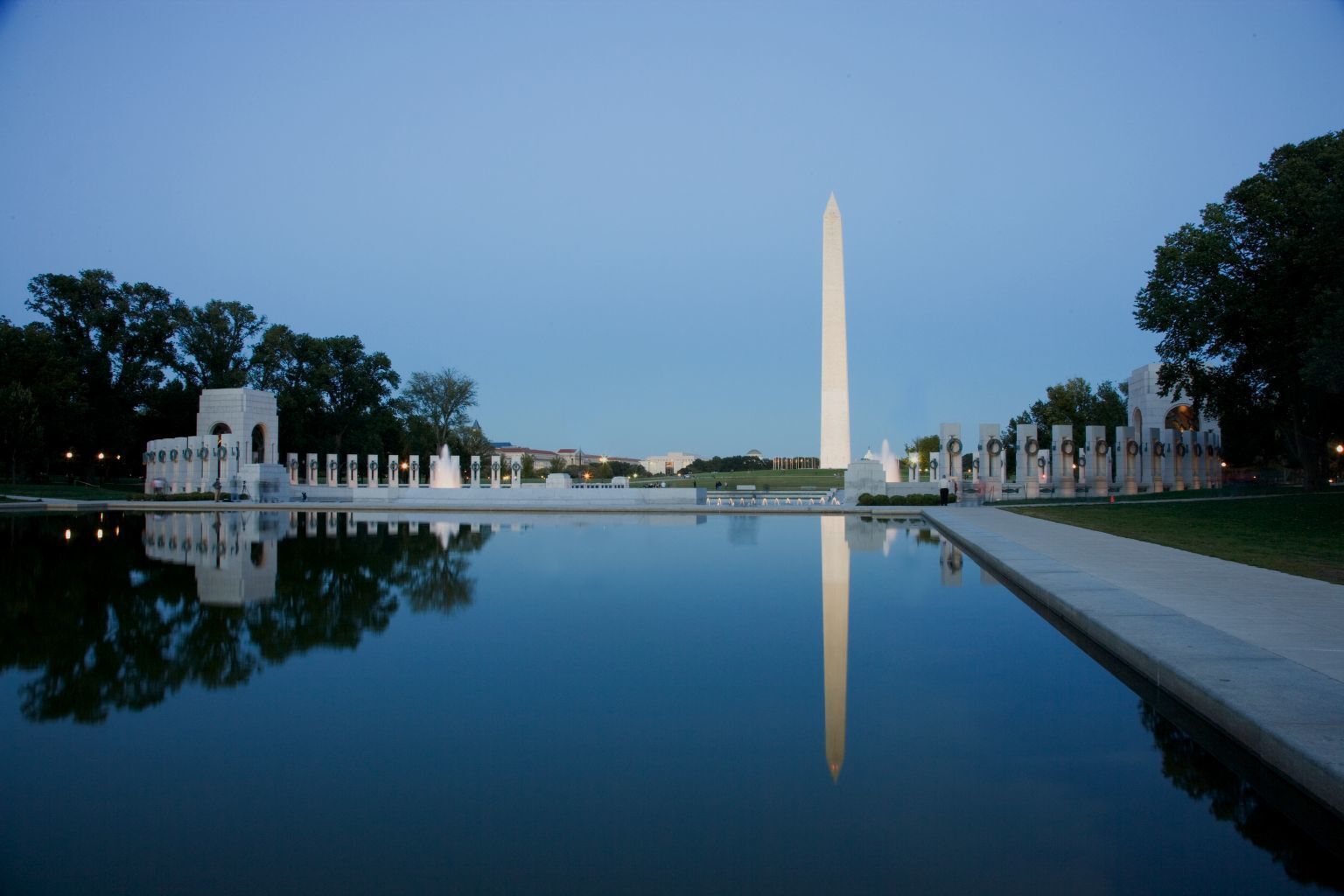 The Washington Monument at night reflected in the still water of the Reflecting Pool.