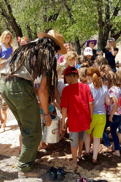 Children stomp in mud to make adobe bricks