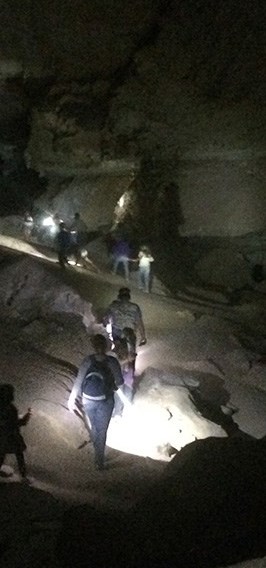 Hikers with flashlights explore a cave