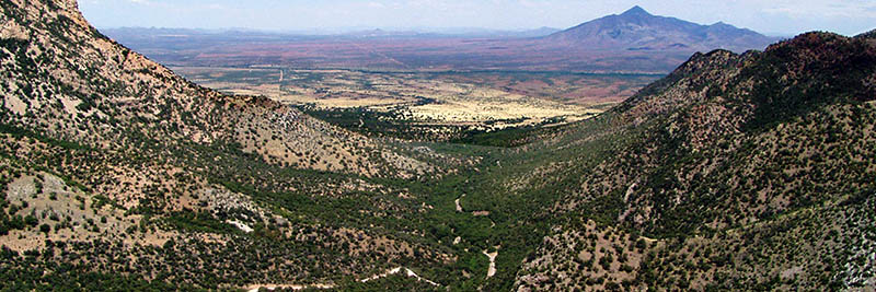 A wide canyon with a mountain peak in the background A wide canyon with a mountain peak in the background