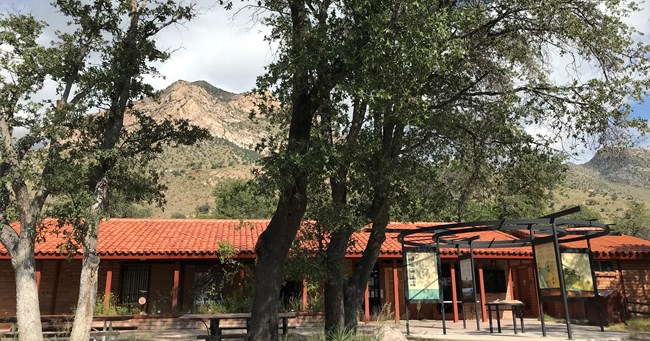 Red adobe brick building with mountain peak in the background.