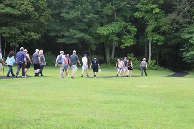 Park Ranger leads group of visitors into a tree line