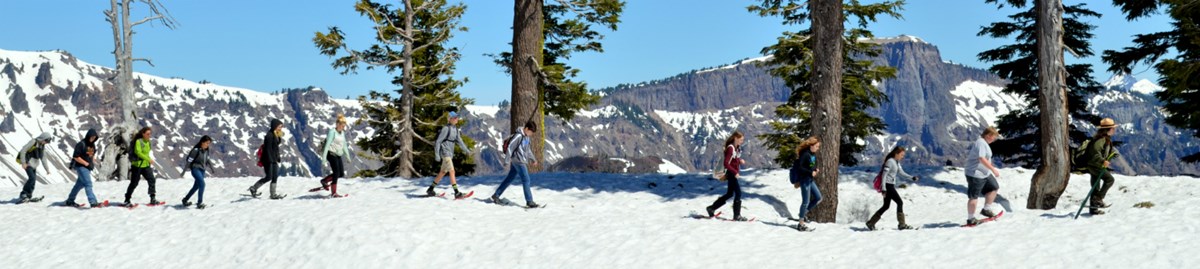 Students follow a ranger along the rim of the Crater Lake caldera on a field trip. Students follow a ranger along the rim of the Crater Lake caldera on a field trip.