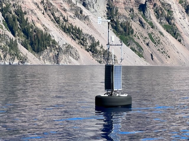 weather station with wind and other instruments on a black base with two solar panels  in Crater Lake