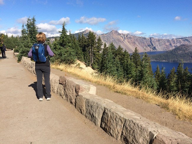 Person walking Rim Village Promenade with Crater Lake and Wizard Island in view