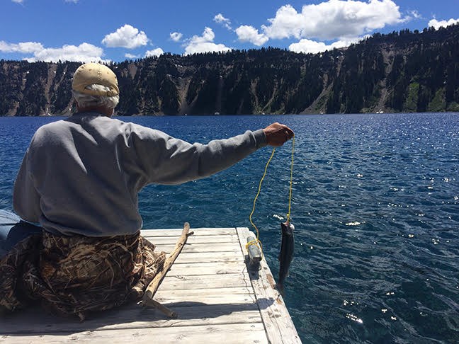 Visitor holds fish caught from Wizard Island Dock