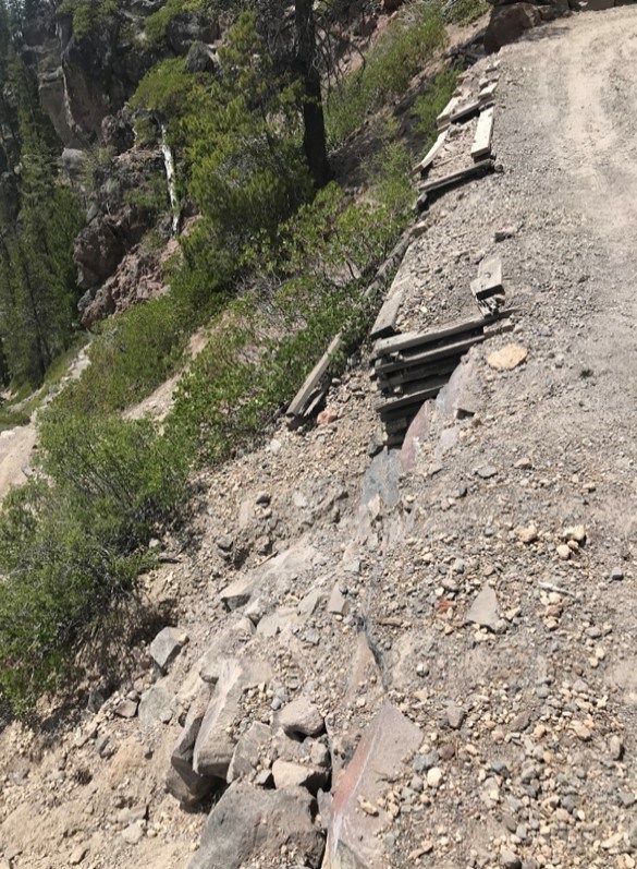 wooden cribbing retaining walls along a trail that are showing signs of failure as they are leaning away from the trail surface