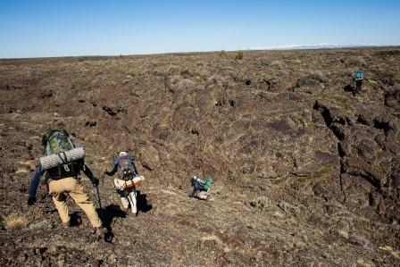 backpackers crossing lava