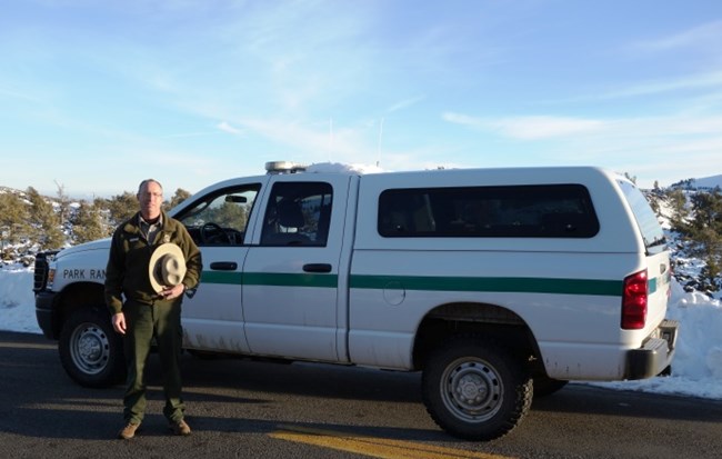 park ranger standing next to a law enforcement vehicle