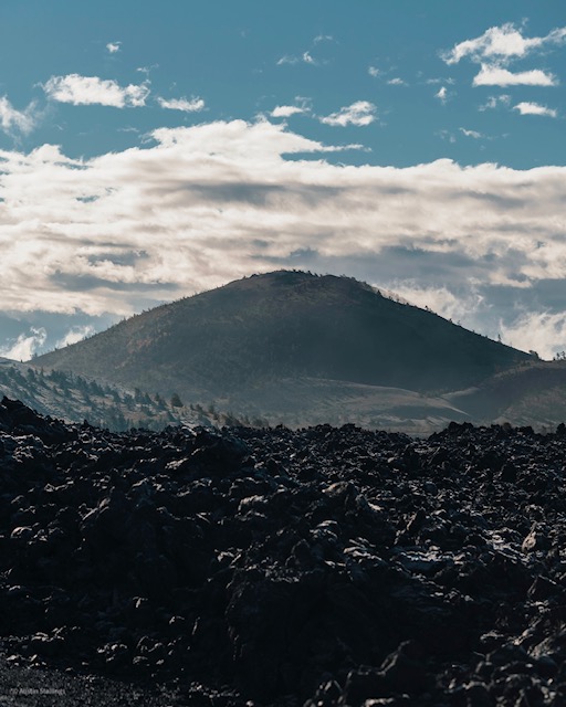 Big Cinder Butte- Craters of the Moon Black cinder cone on a partly cloudy day