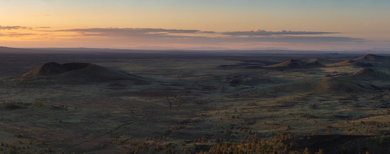 A panoramic view of the Craters of the Moon landscape at sunrise.