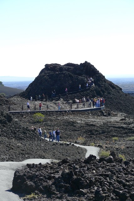 a line of students and teachers walking on a winding paved path from a small inactive
spatter cone volcano