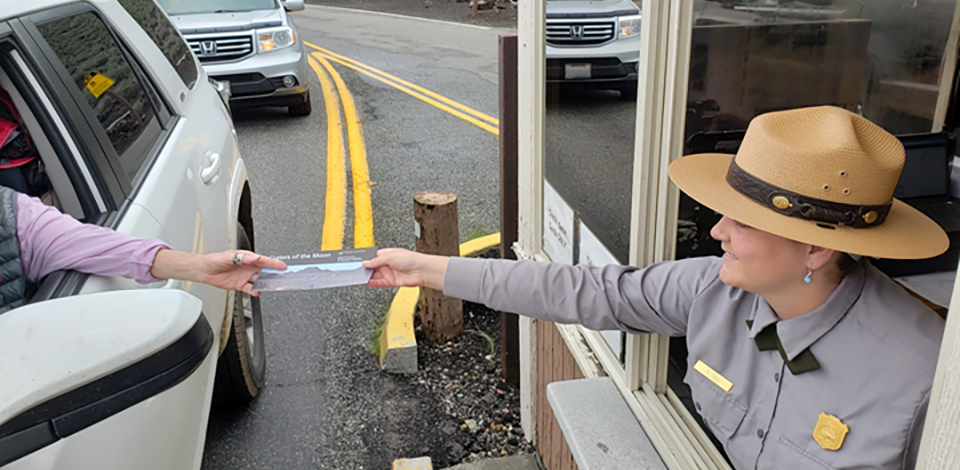 a park ranger gives a visitor a park brochure at the fee entrance station