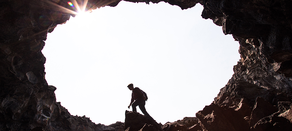 Hiker exploring Indian Tunnel with sunburst