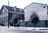 Incompatible New Construction. <three photo series>  The playground adjacent to this 1923 recreation center is important in defining the character of the site and an integral feature of the complex.  As part of a rehabilitation project, thirteen new townhouses were built on the playground. Because of their size and placement on the site, this new infill construction effectively alters the playground and its historic relationship to the recreation center buildings. Reducing the number of townhouses, together with sensitive siting, would have helped retain an open feeling on the corner of the property and provided a vista to the historic buildings.  Photos: NPS files